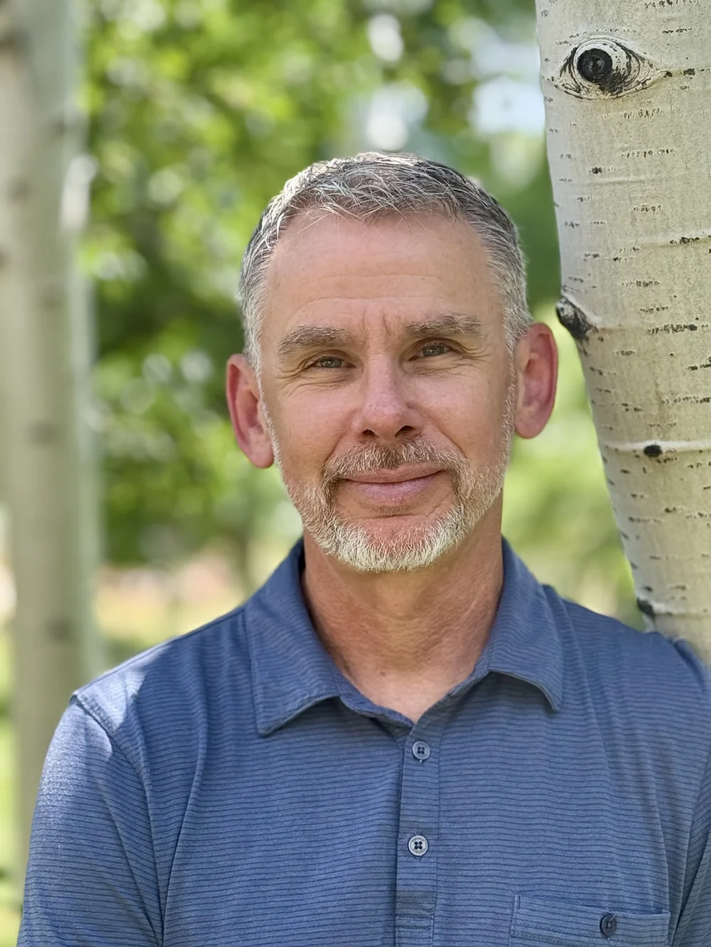 Scott Burd standing beside an aspen tree