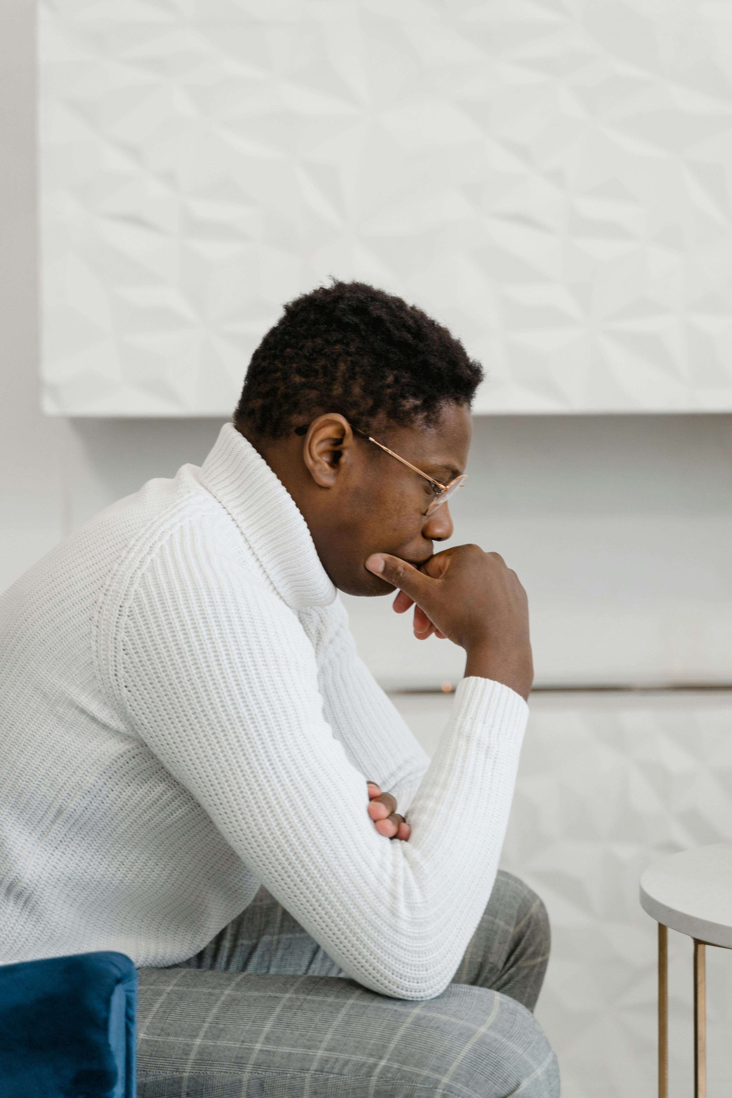 Man sitting on a chair with his hand on his chin, deep in thought.