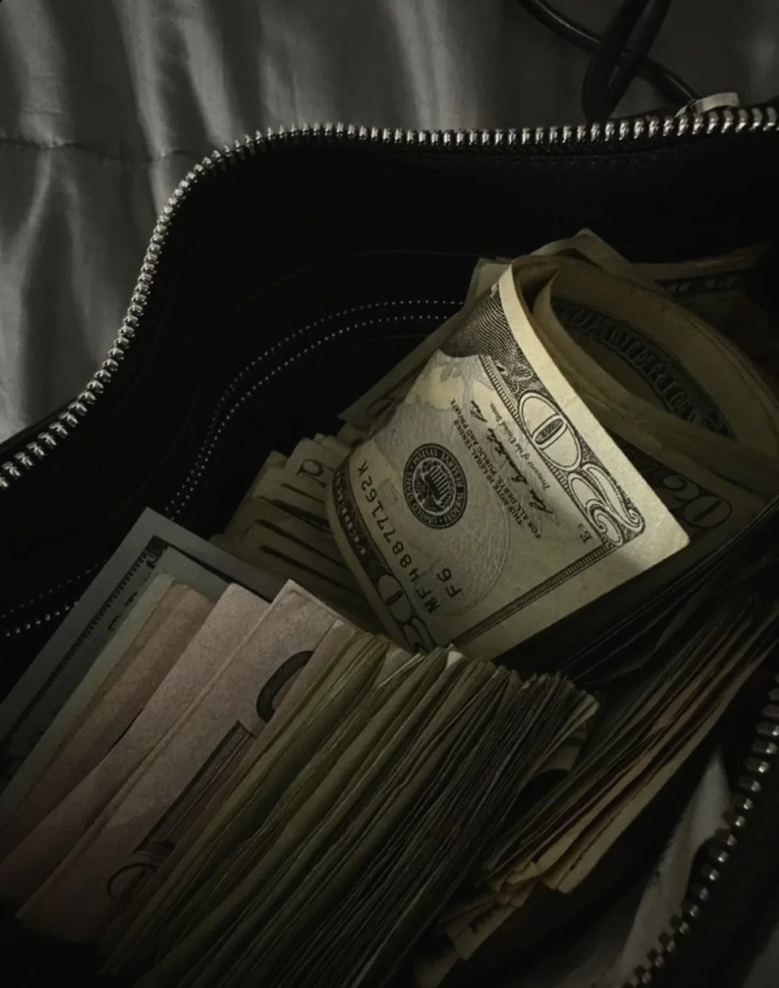Inside a bag with stacks of U.S. currency, including folded hundred-dollar bills and smaller bills.