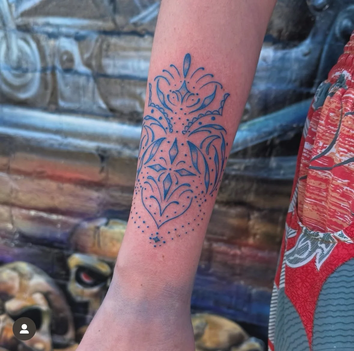 Arm tattoo with intricate blue line design and abstract patterns.