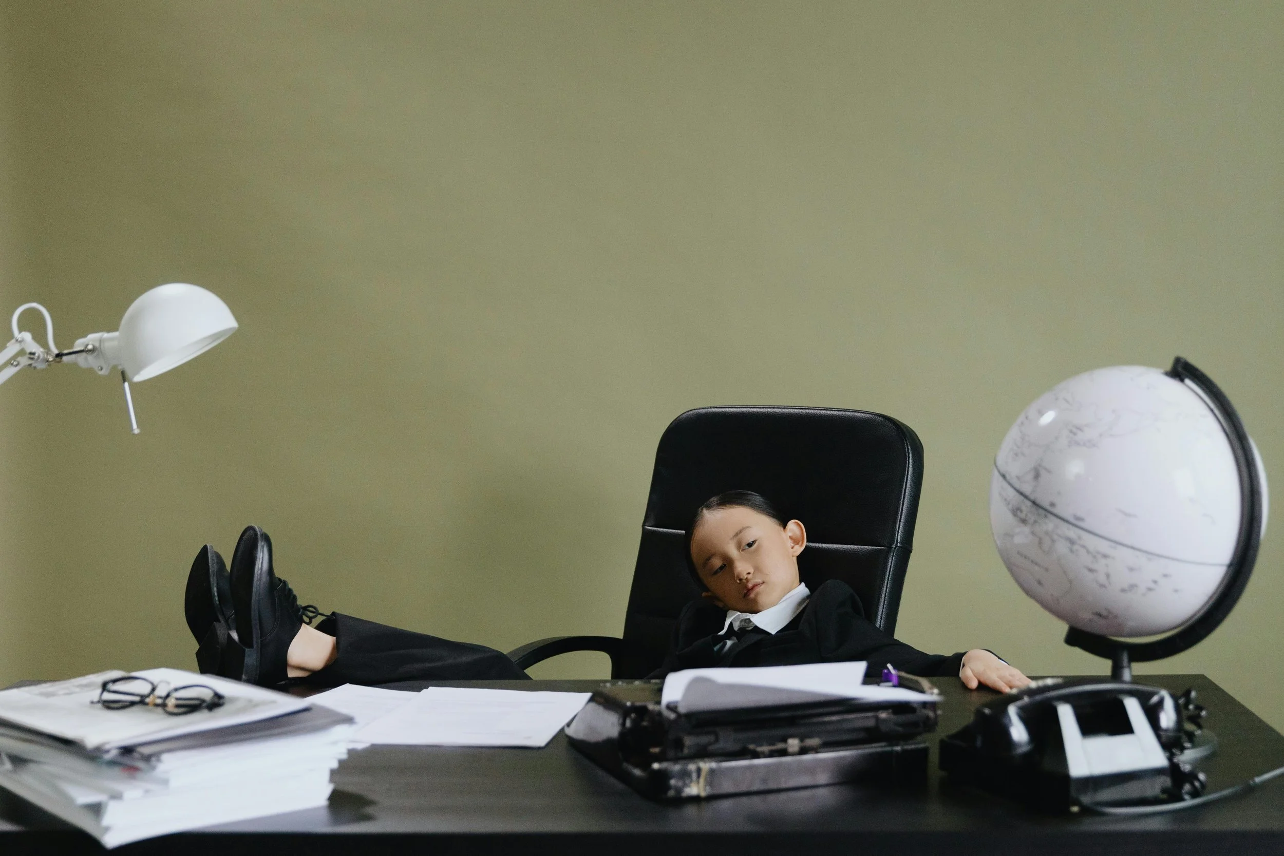 A child sat confidently in an executive office