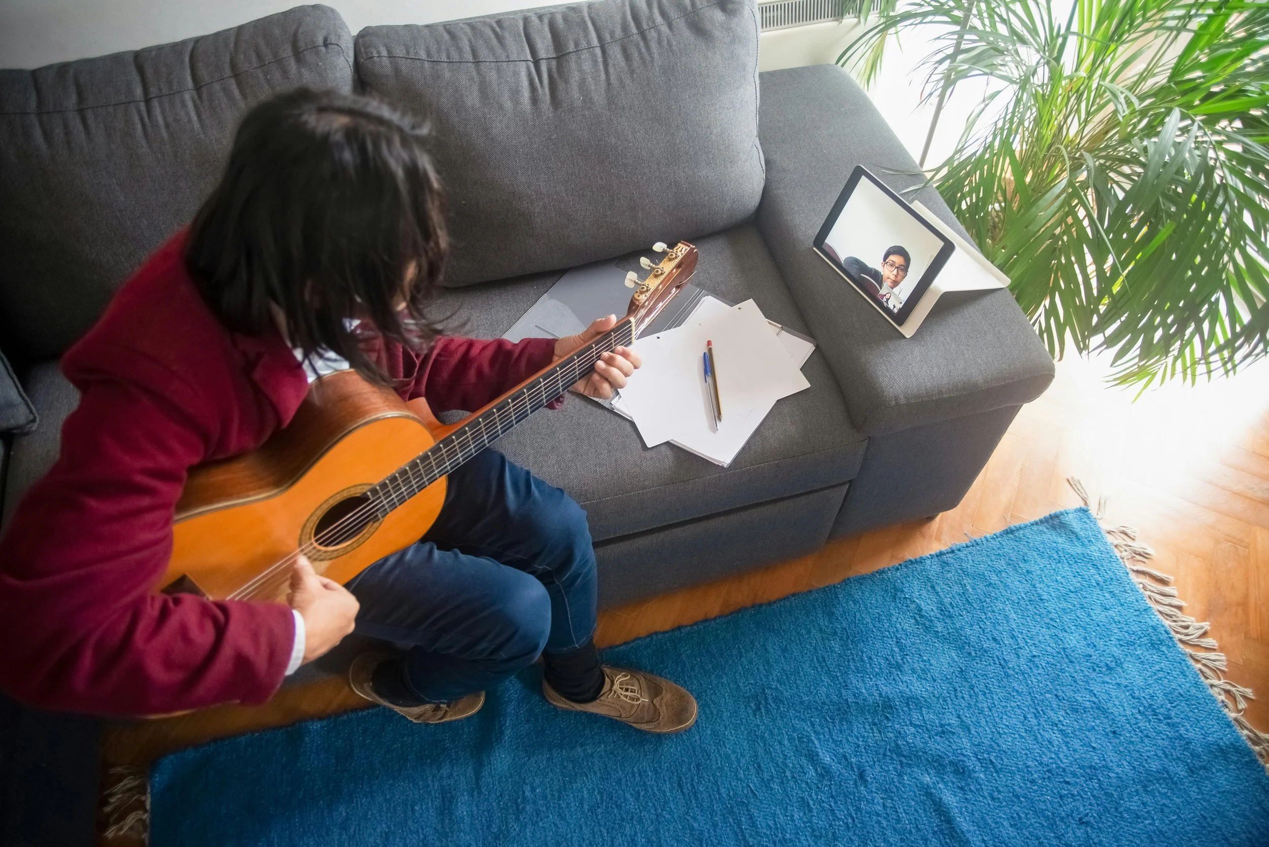 A student plays guitar to his online teacher
