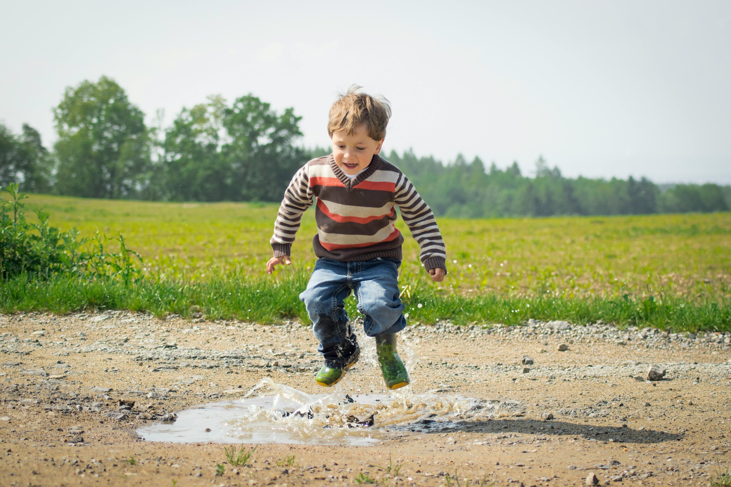 A child jumps in a puddle
