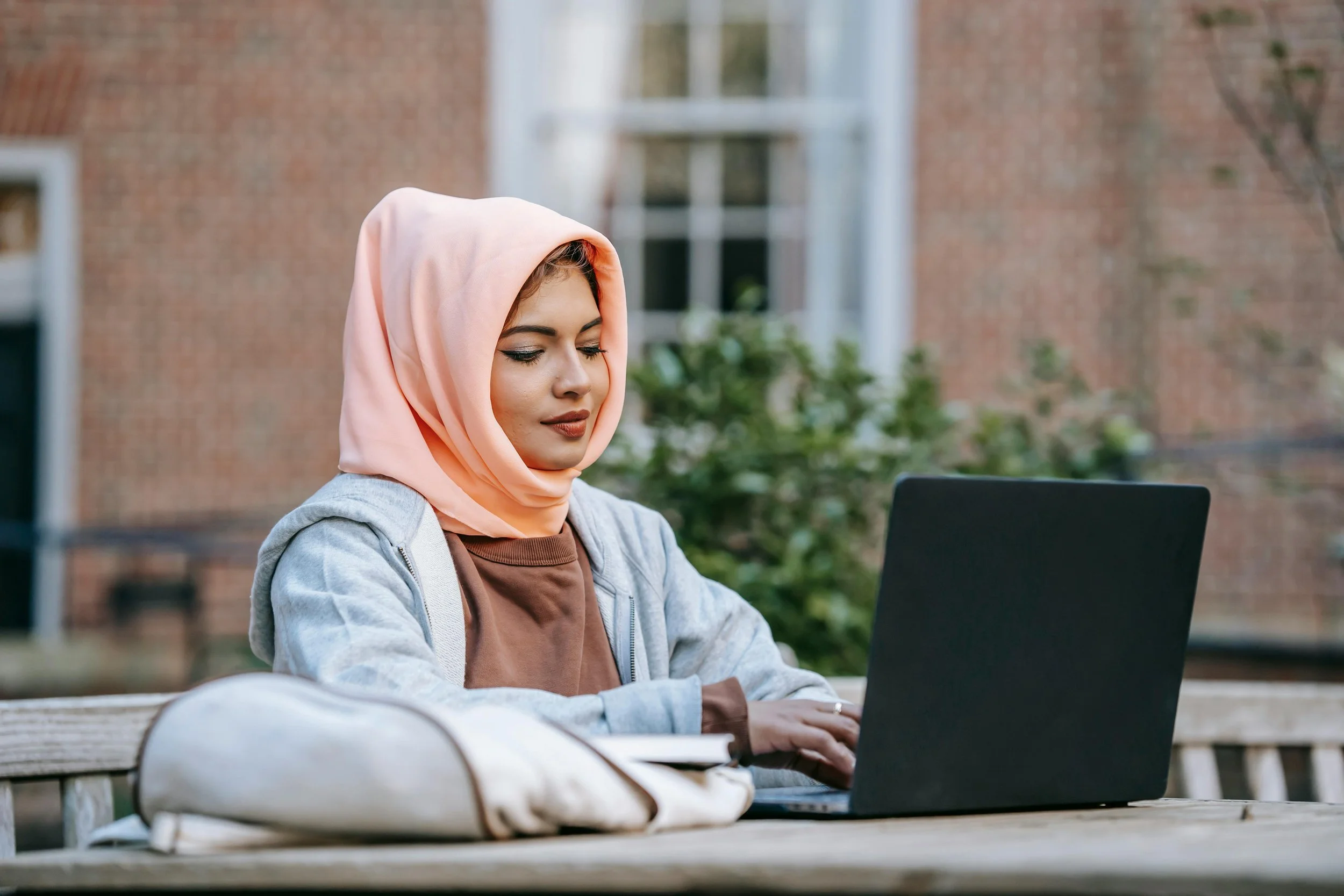 A student sits outside on their laptop