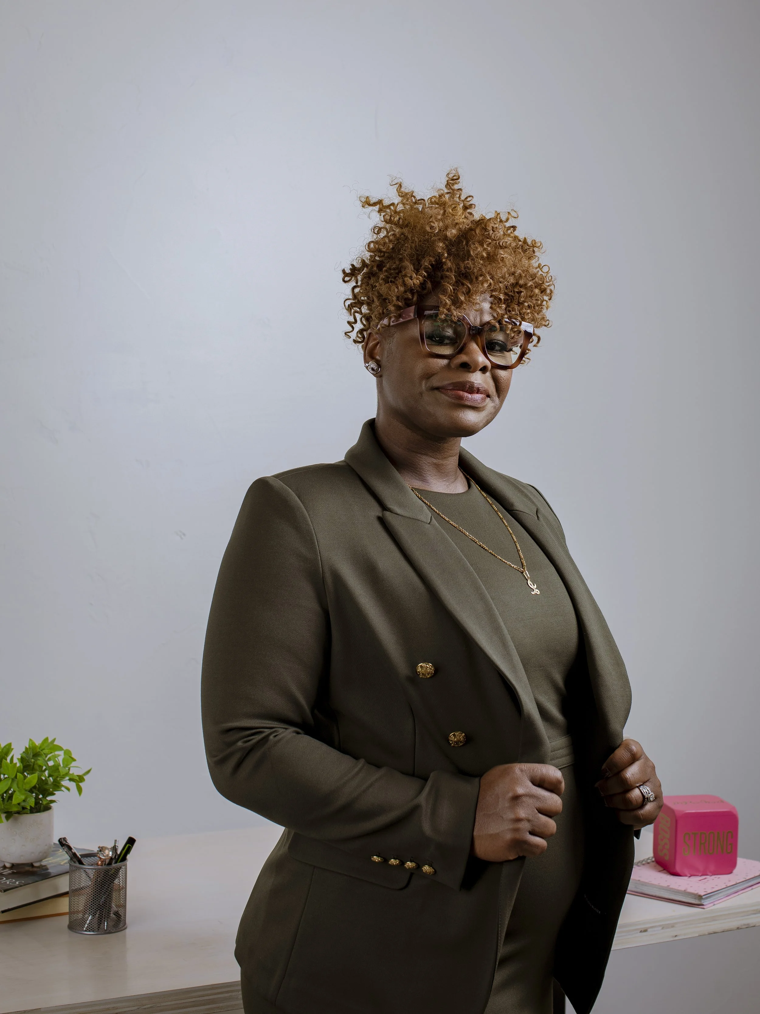 Black woman standing against a desk in a power pose