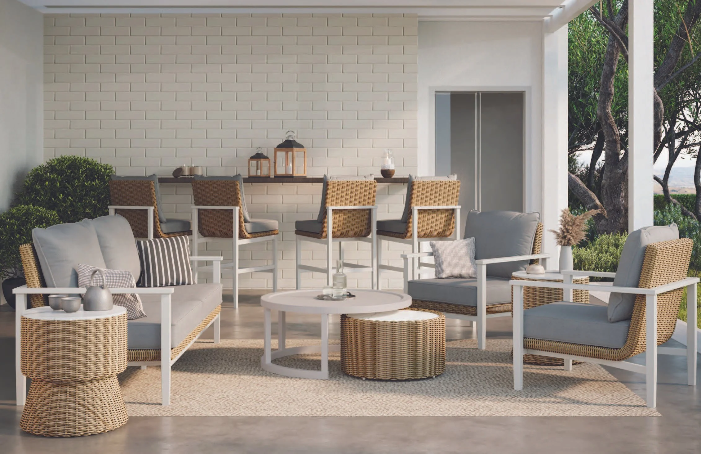 A modern outdoor patio area with beige and white furniture, wicker chairs, and a wooden table with decorative lanterns, illuminated by natural light and surrounded by green trees.