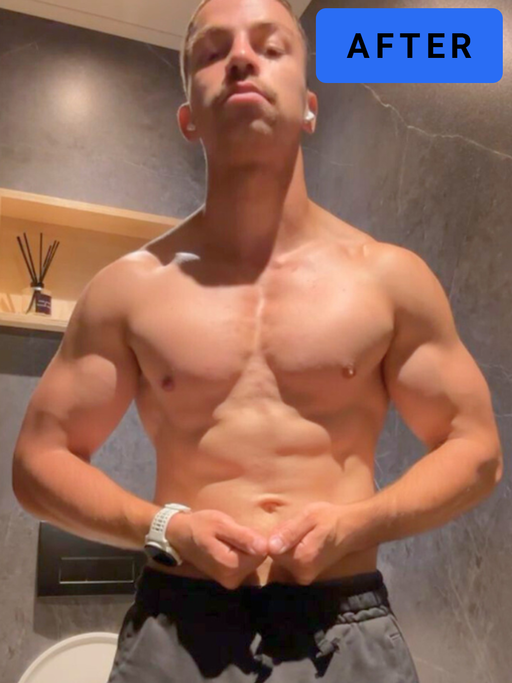 Een man poseert shirtloos, maakt een hartvorm met zijn handen, en heeft een korte kapsel. Er staat een blauwe sticker met het woord 'AFTER' op de foto.