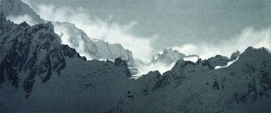 Snow-capped mountain range with clouds in the sky.