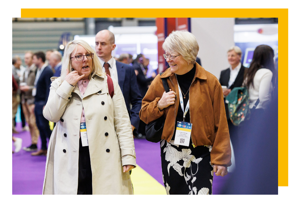 A person miming a phone with their hand to another smiling visitor