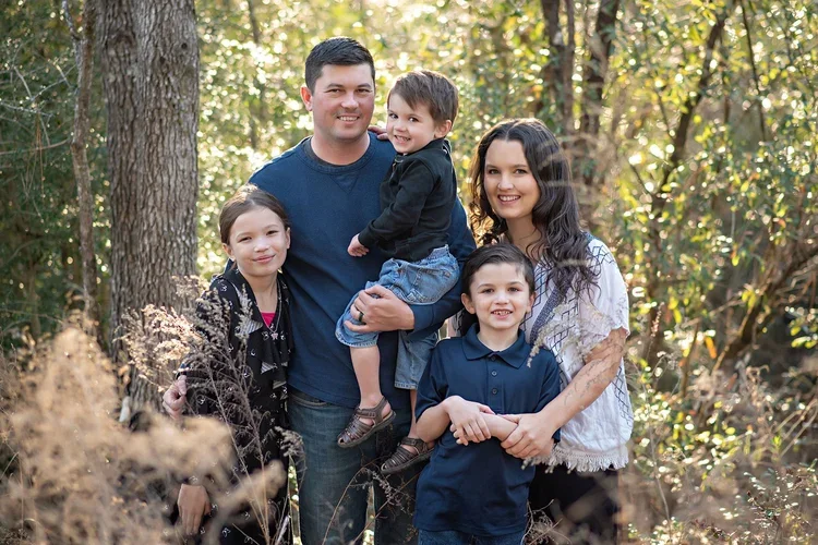 Family of five standing together in wooded Palm City area during portrait session