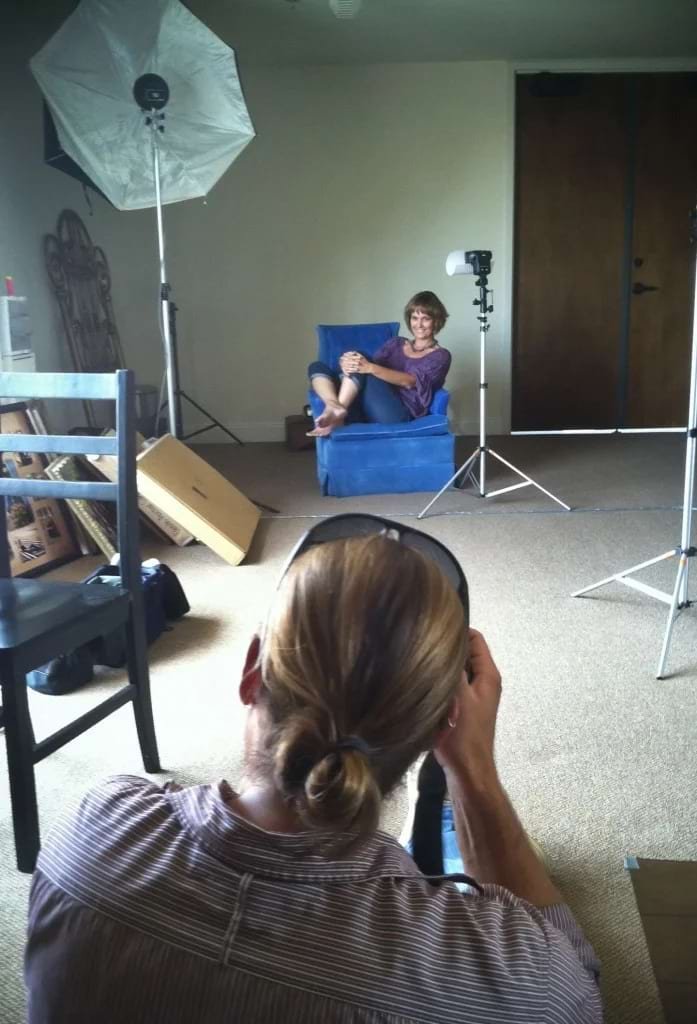 Diane Dultmeier being photographed for a newspaper article, seated in a studio setup with lighting gear