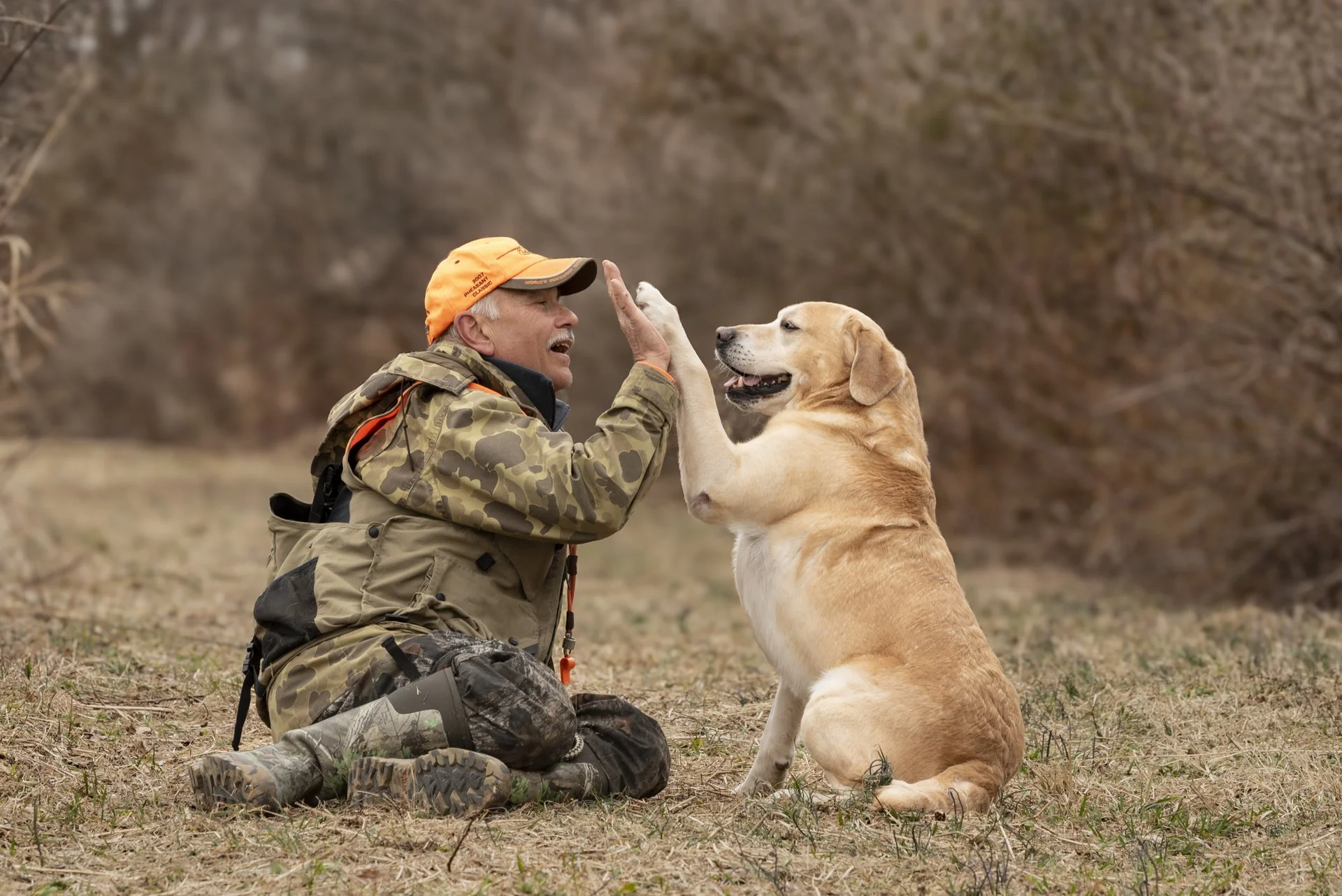 A man sharing a high-five with his yellow Labrador.