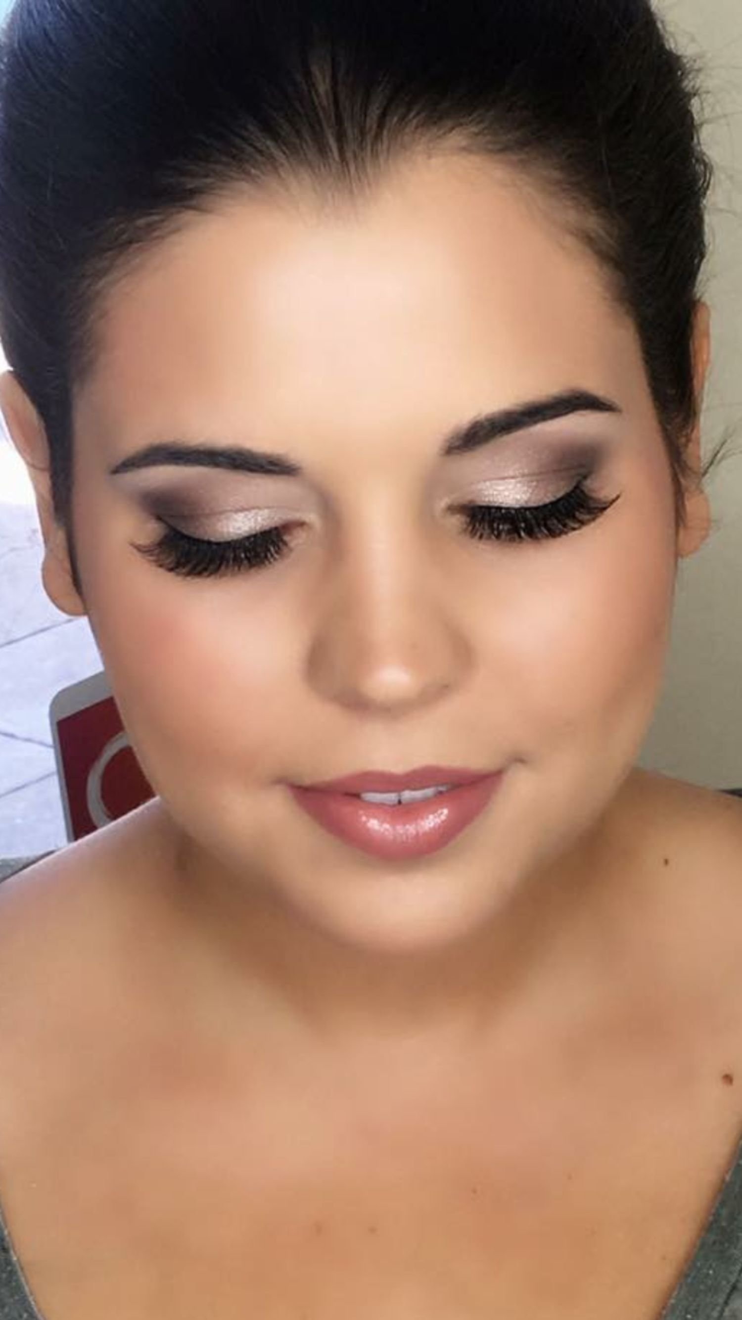 Close-up of a woman with closed eyes, wearing makeup and dark hair pulled back.