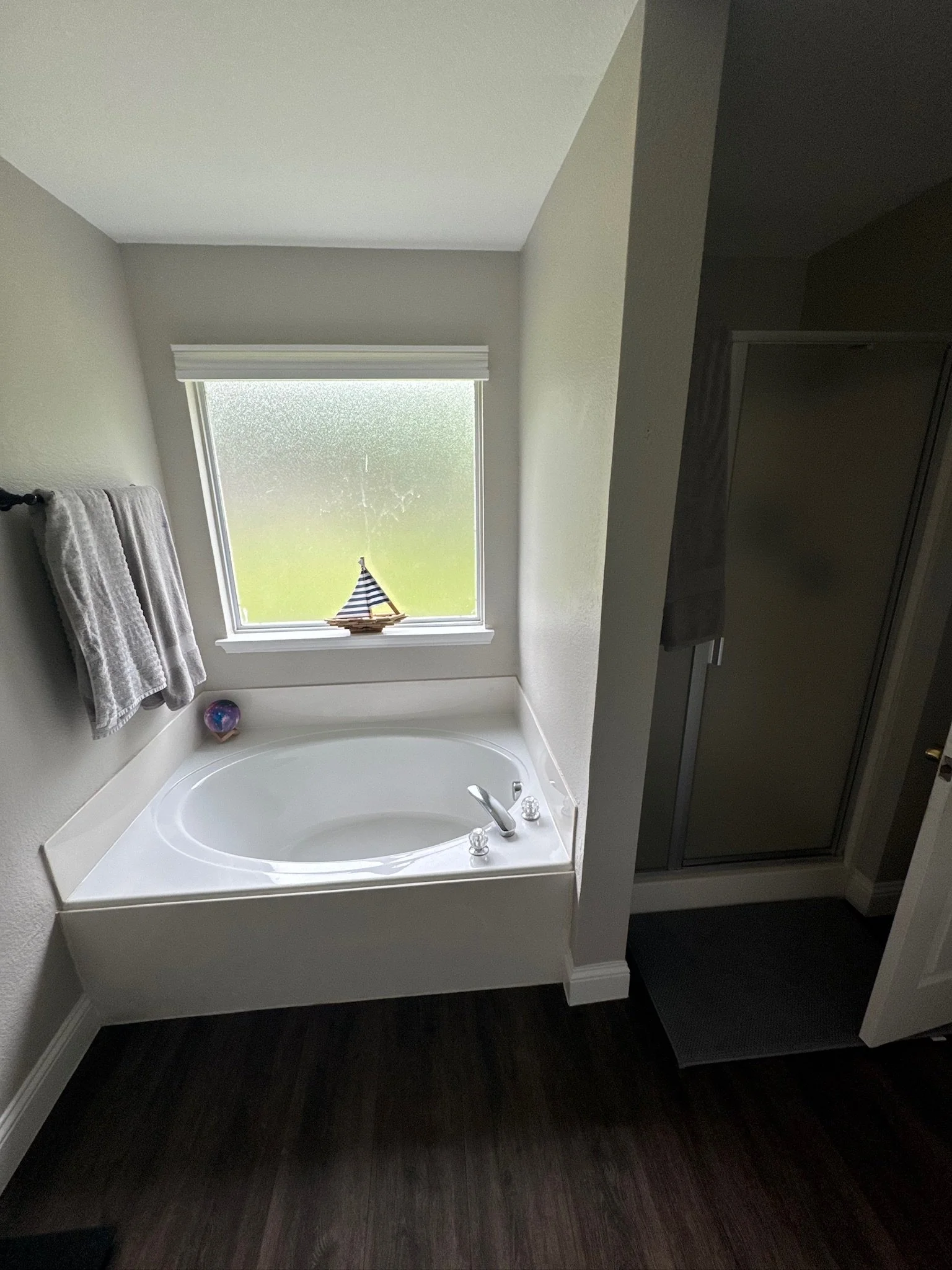 Bathroom with a bathtub near a frosted window, a basket, and towels on a towel rack.