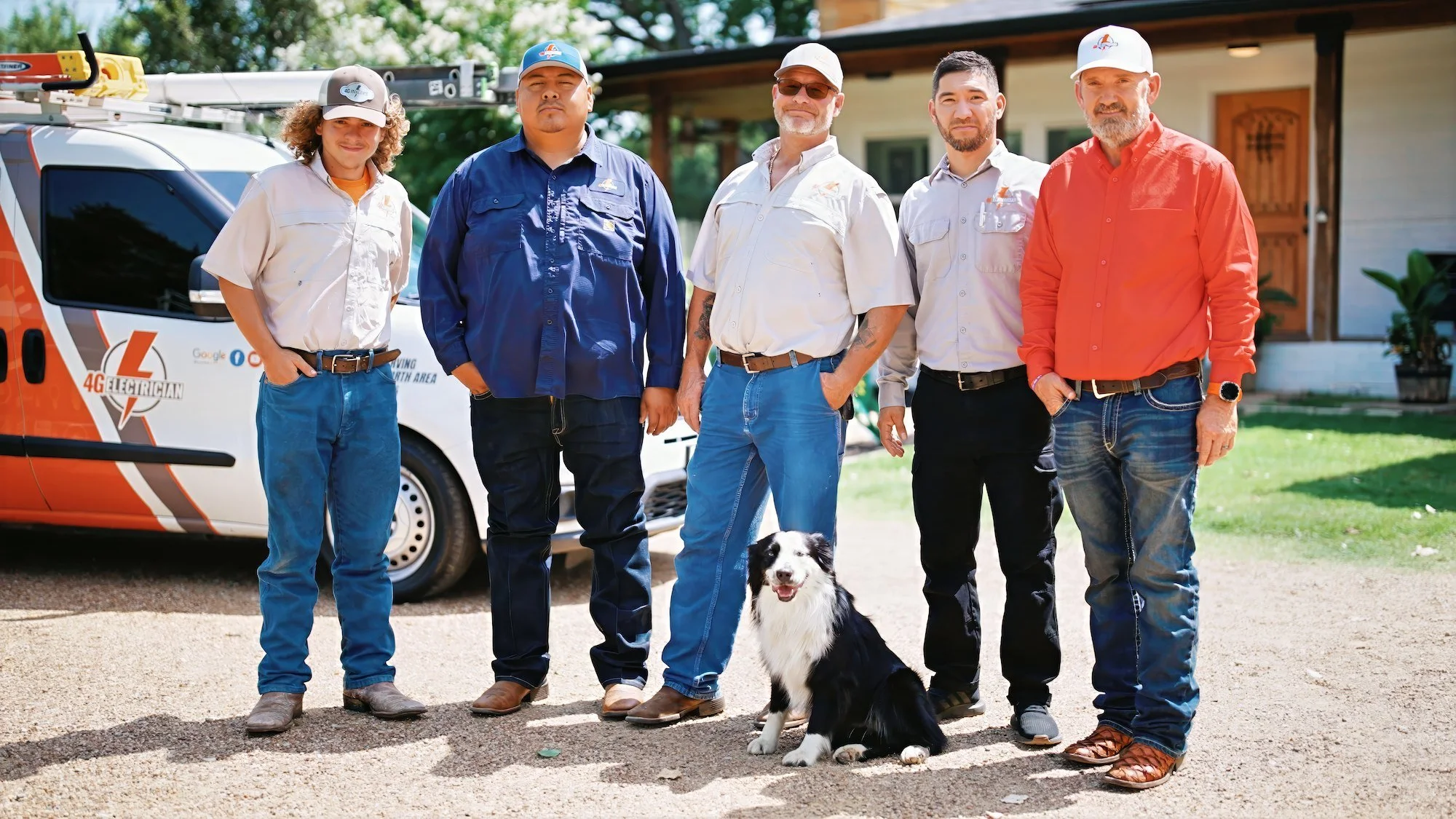 Group of five men standing outdoors in front of a vehicle labeled '4G Electrician' with a Border Collie dog, in a residential area.