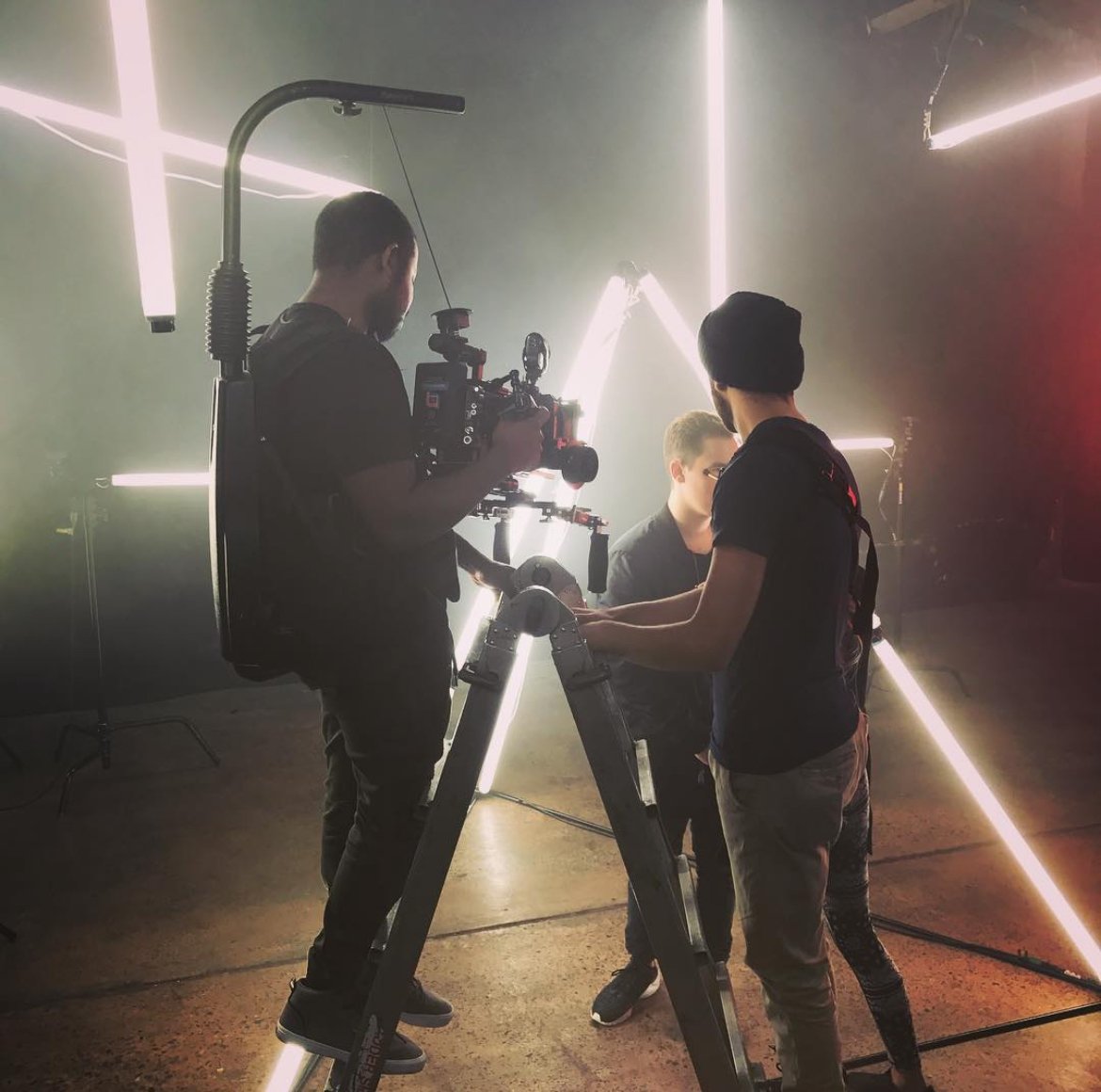 Film crew setting with cameraman filming amid neon light backdrop.