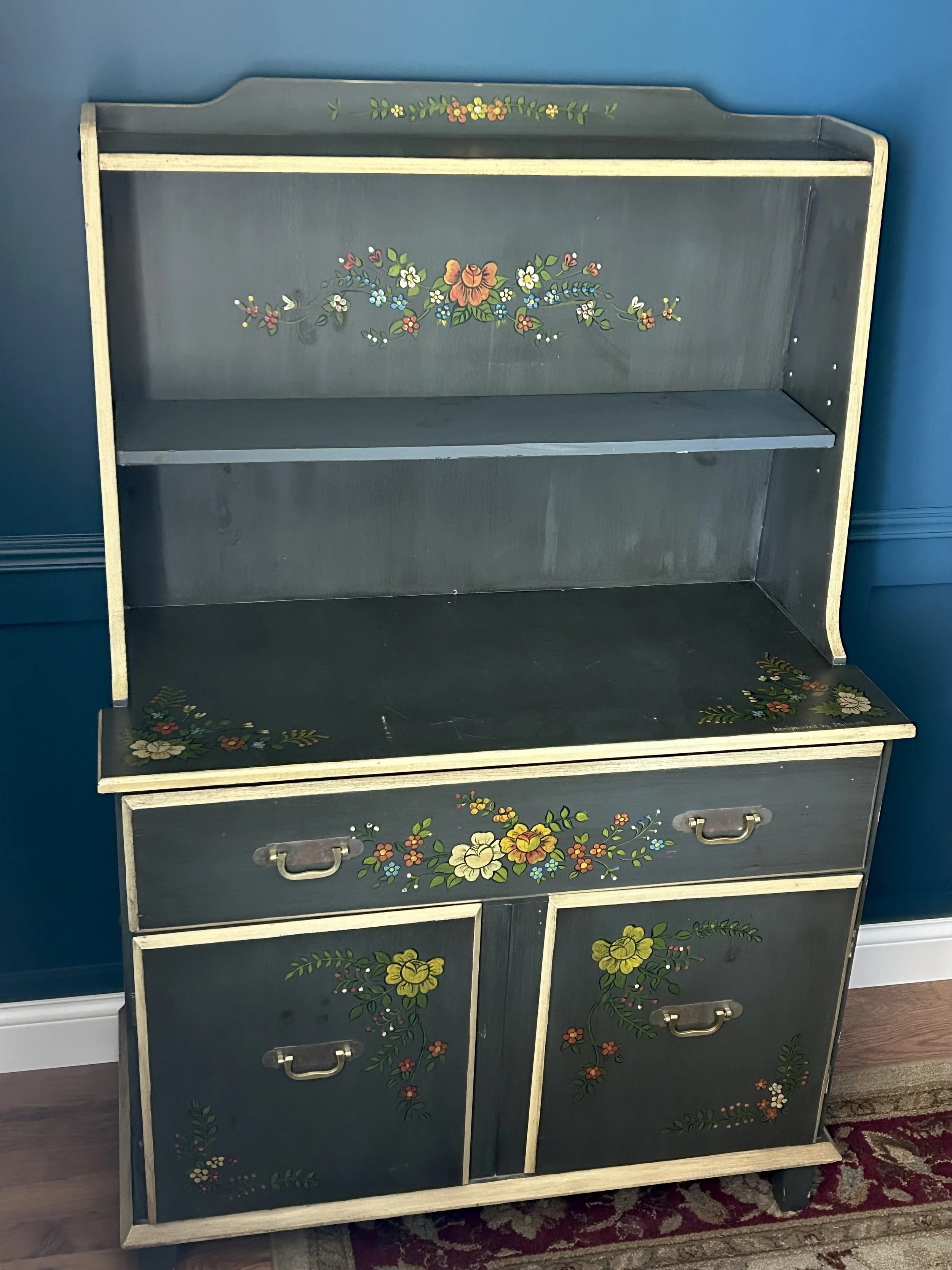 Traditional folk-painted hutch displayed in the study with decorative details and collected treasures.