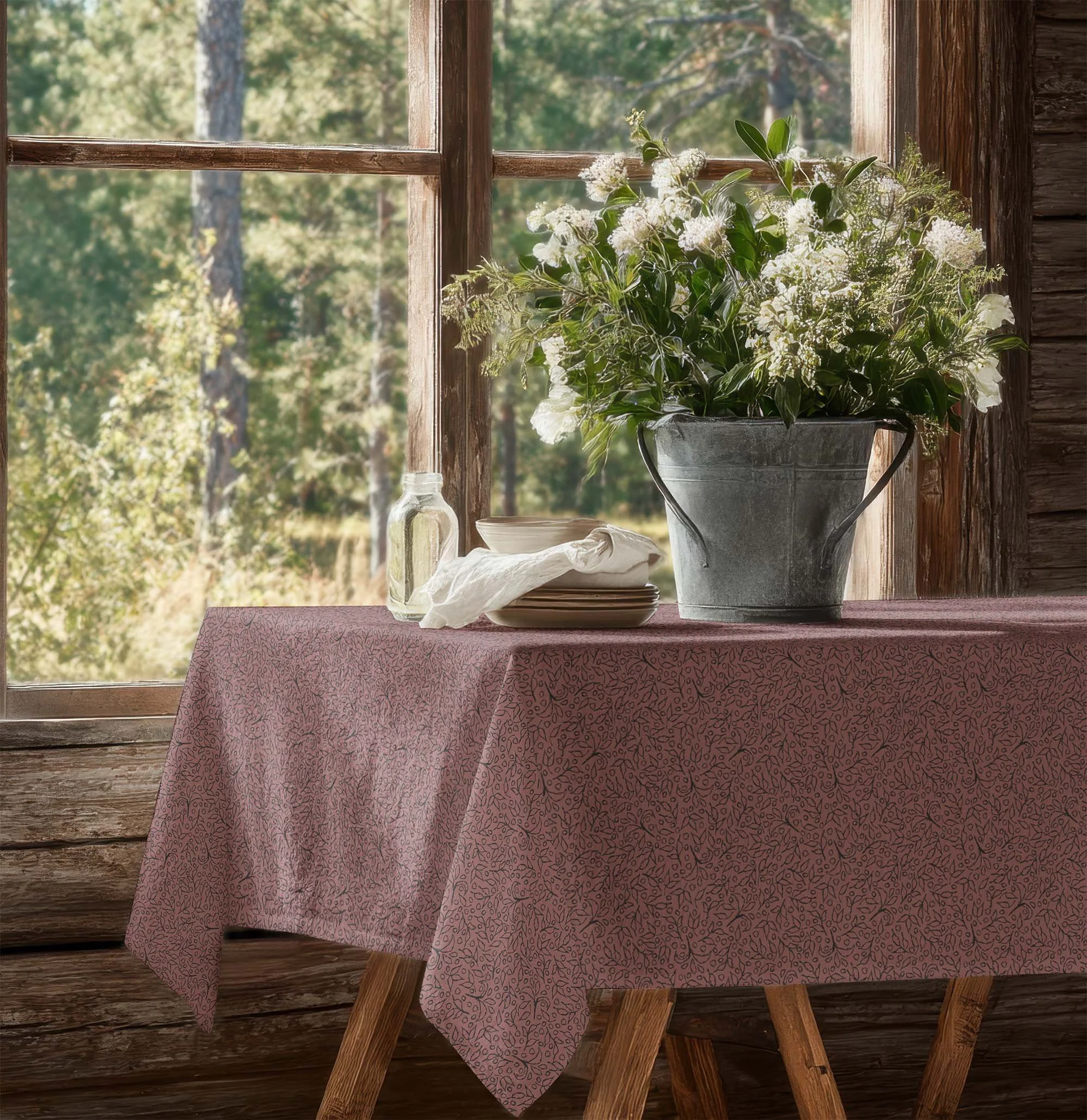 Dusty rose Grove Vine botanical pattern on a tablecloth in a rustic room with a large bouquet of white flowers beside a sunlit window.