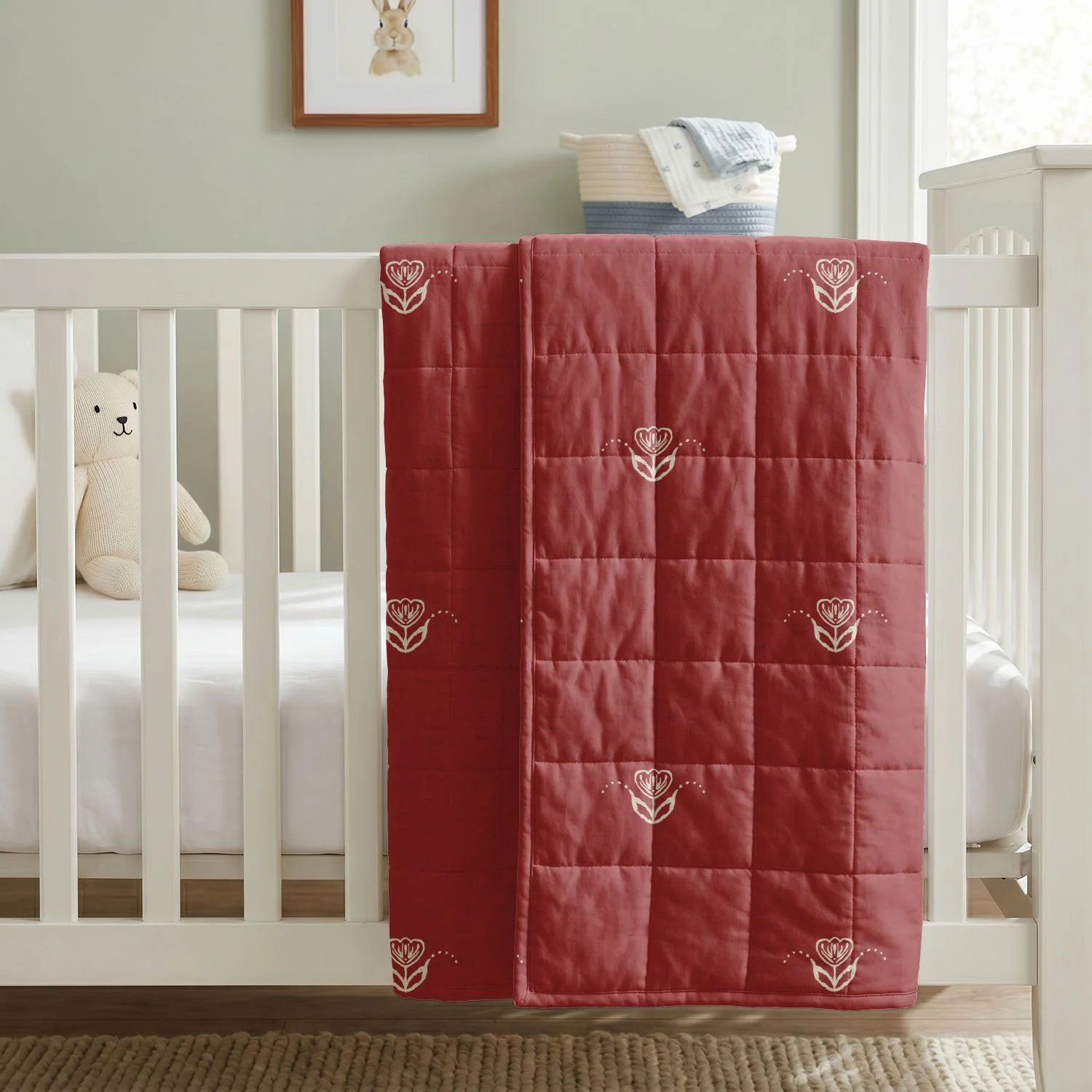 Red and ivory Scandi Tulip floral quilt draped over a white crib in neutral nursery.