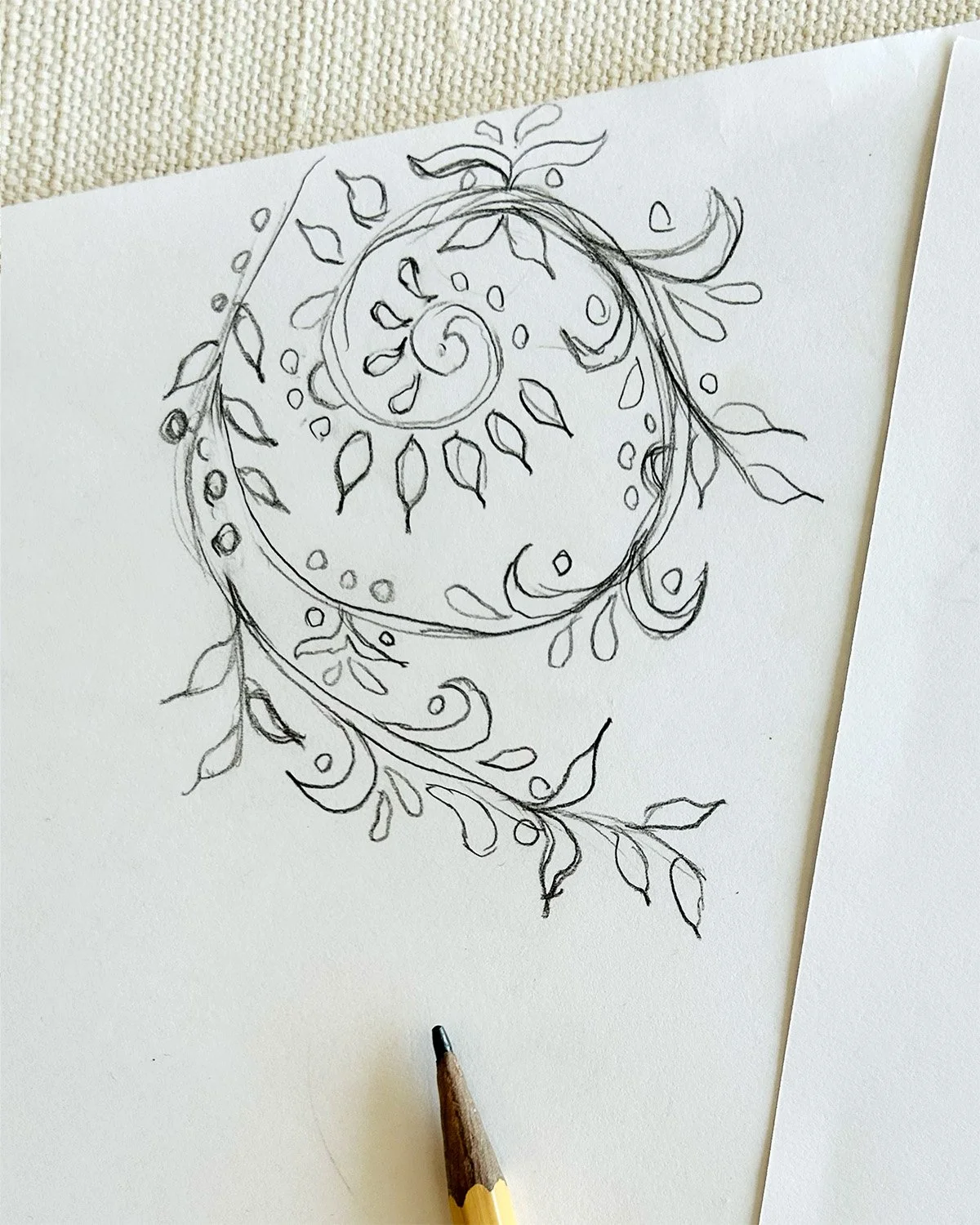 Original pencil sketch of the winding botanical vine that inspired the Grove Vine collection, shown beside a drawing pencil.