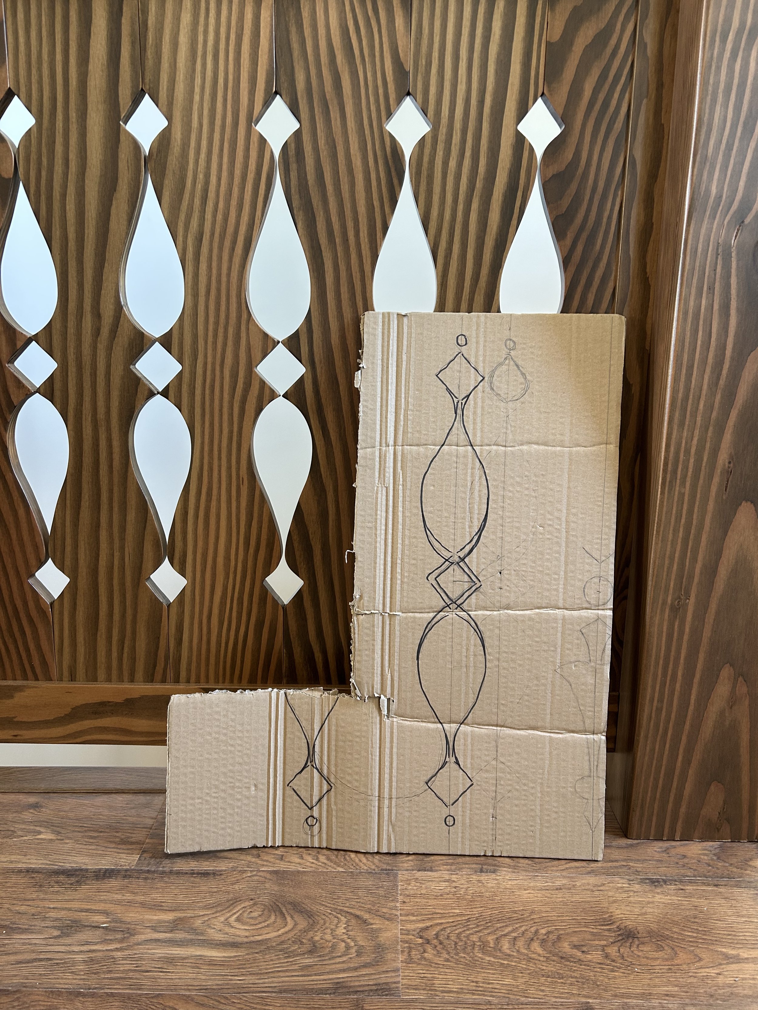 Original cardboard design sketch displayed beside the completed custom wooden stair railing.