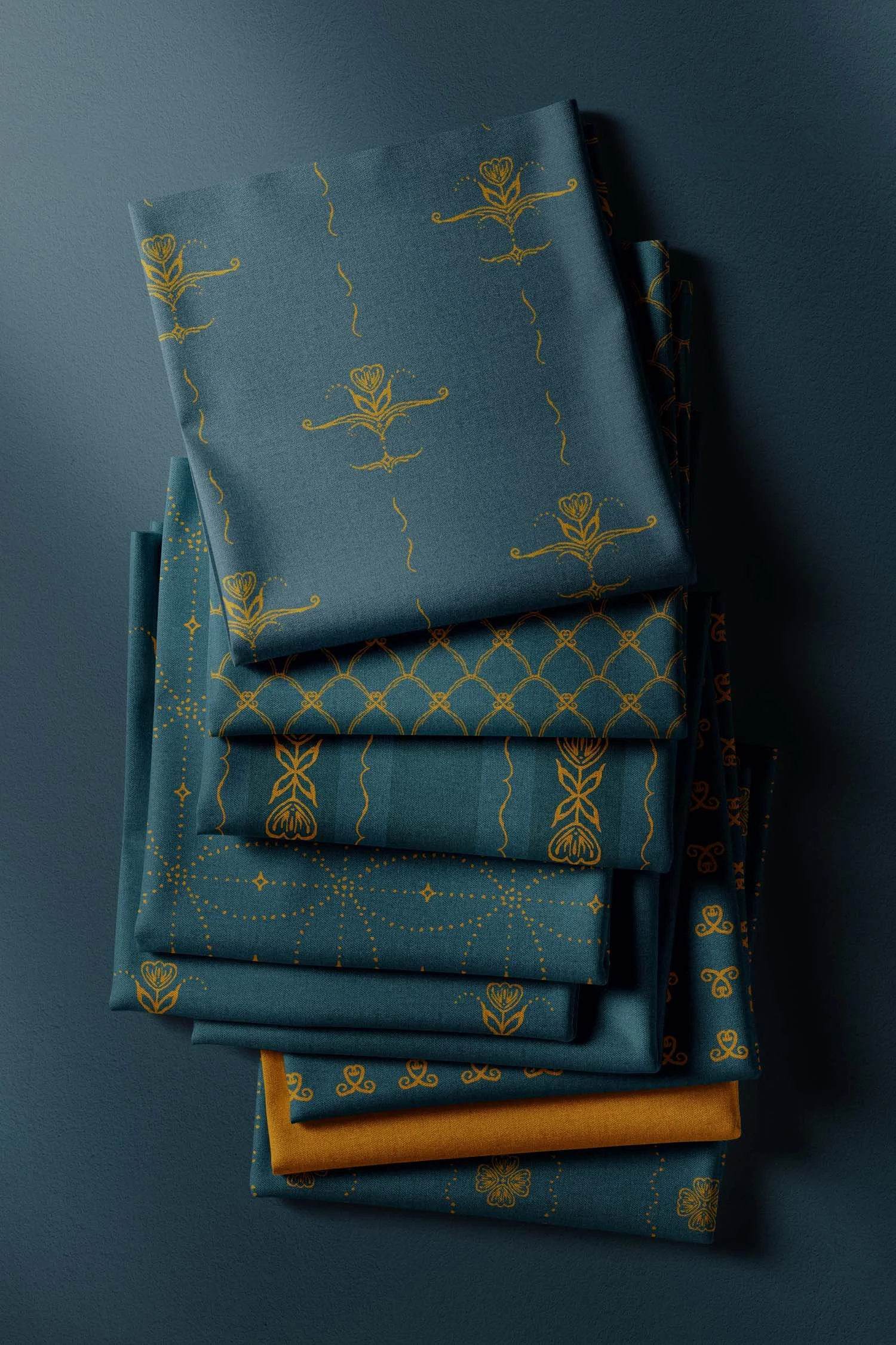 Stack of coordinating Scandi Tulip fabrics in fjord teal and antique gold, showing floral stripes, scalloped geometry, small motifs, and a gold solid.