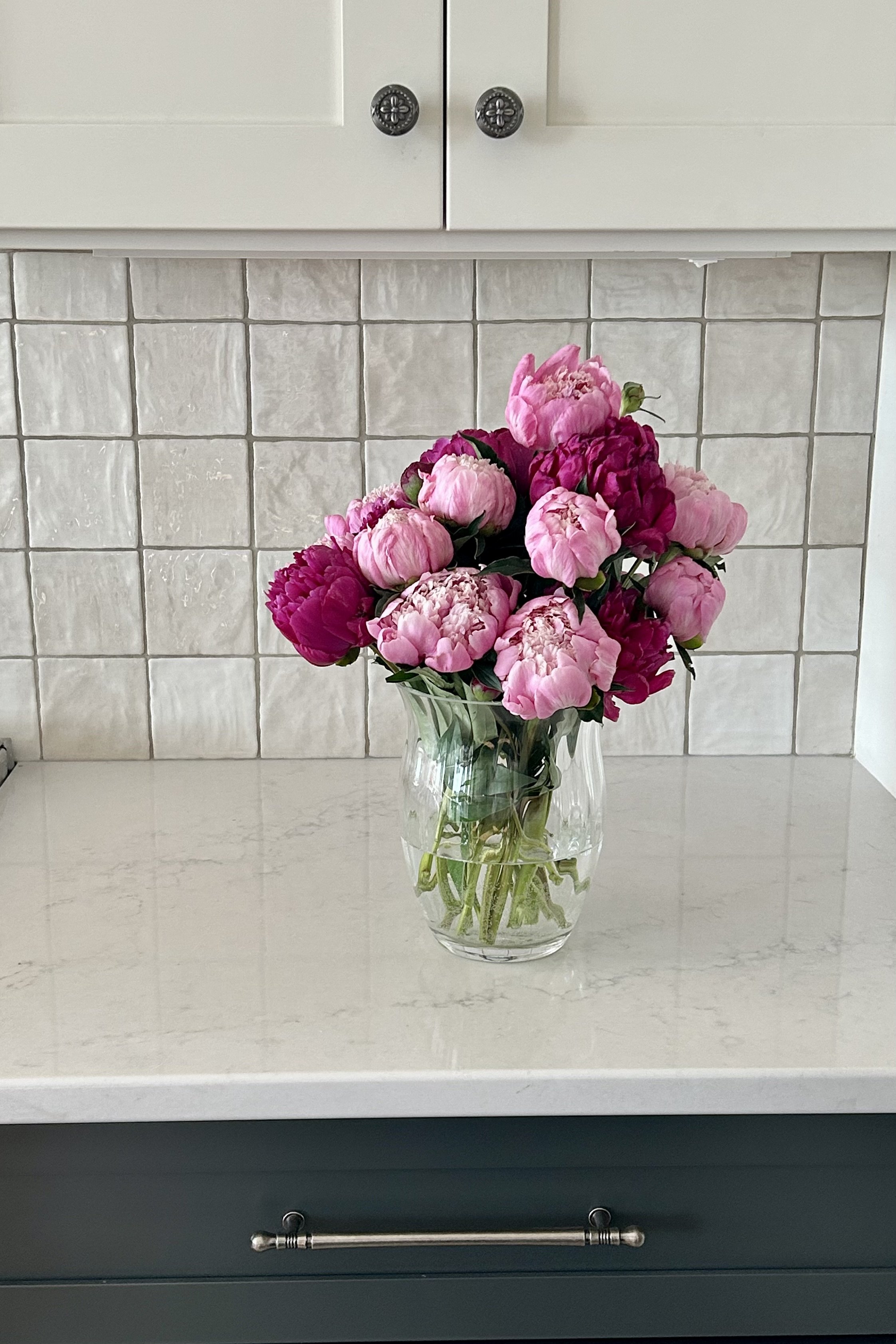 Fresh pink peonies from the family farm displayed beside the kitchen stove.