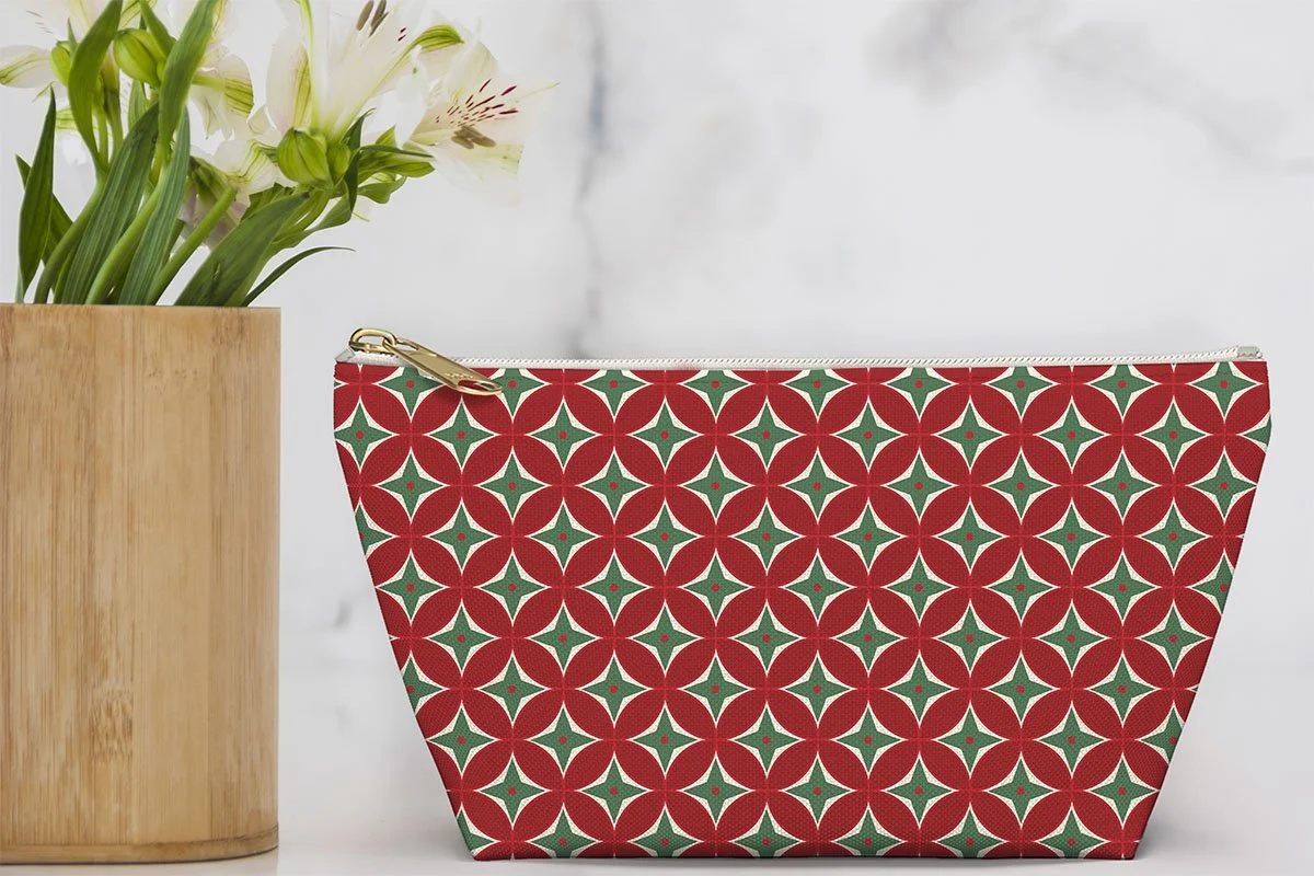 Zipper pouch featuring a red, green and cream geometric star pattern beside a vase of white flowers.