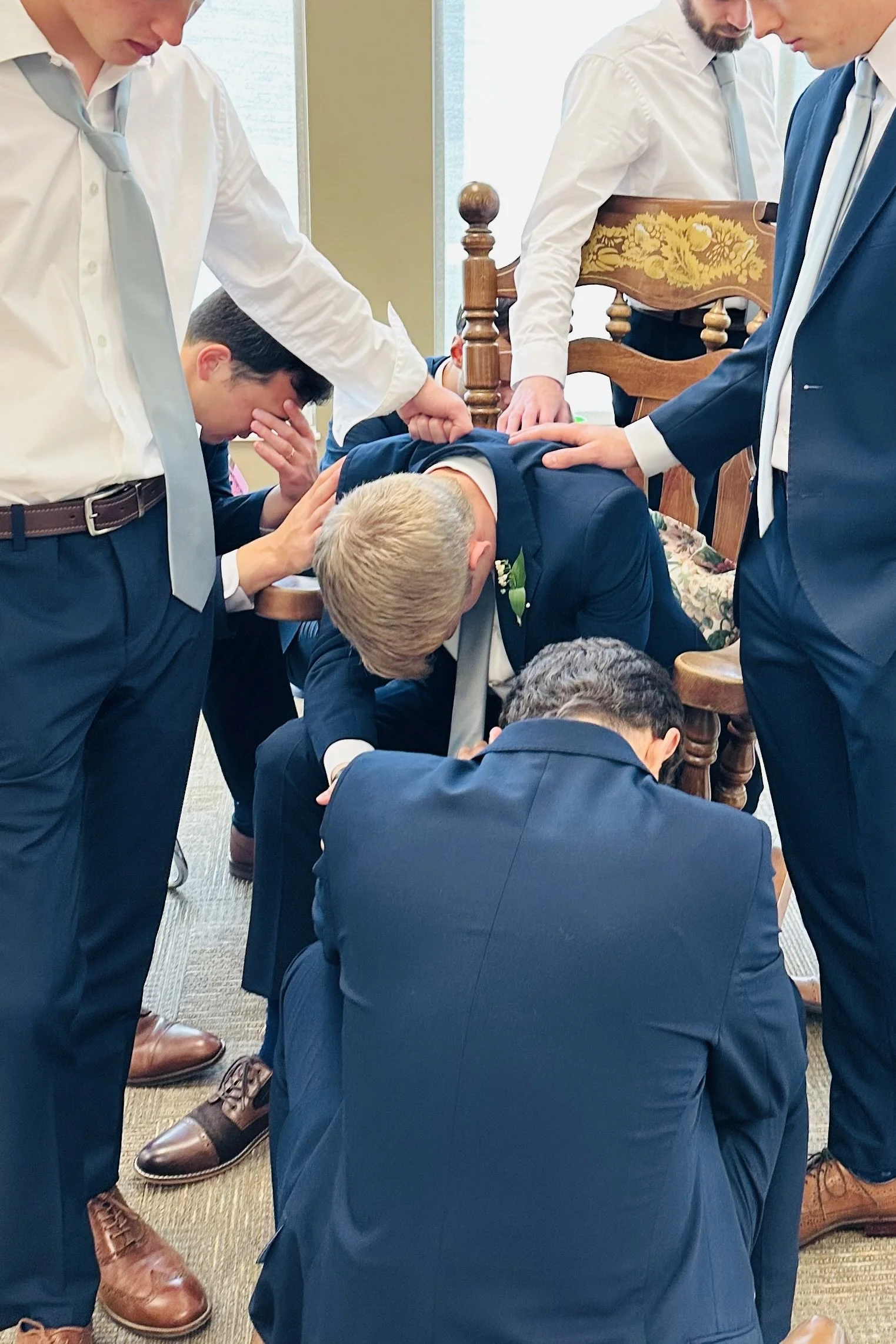 Groomsmen gathered in prayer around the groom before the wedding ceremony.