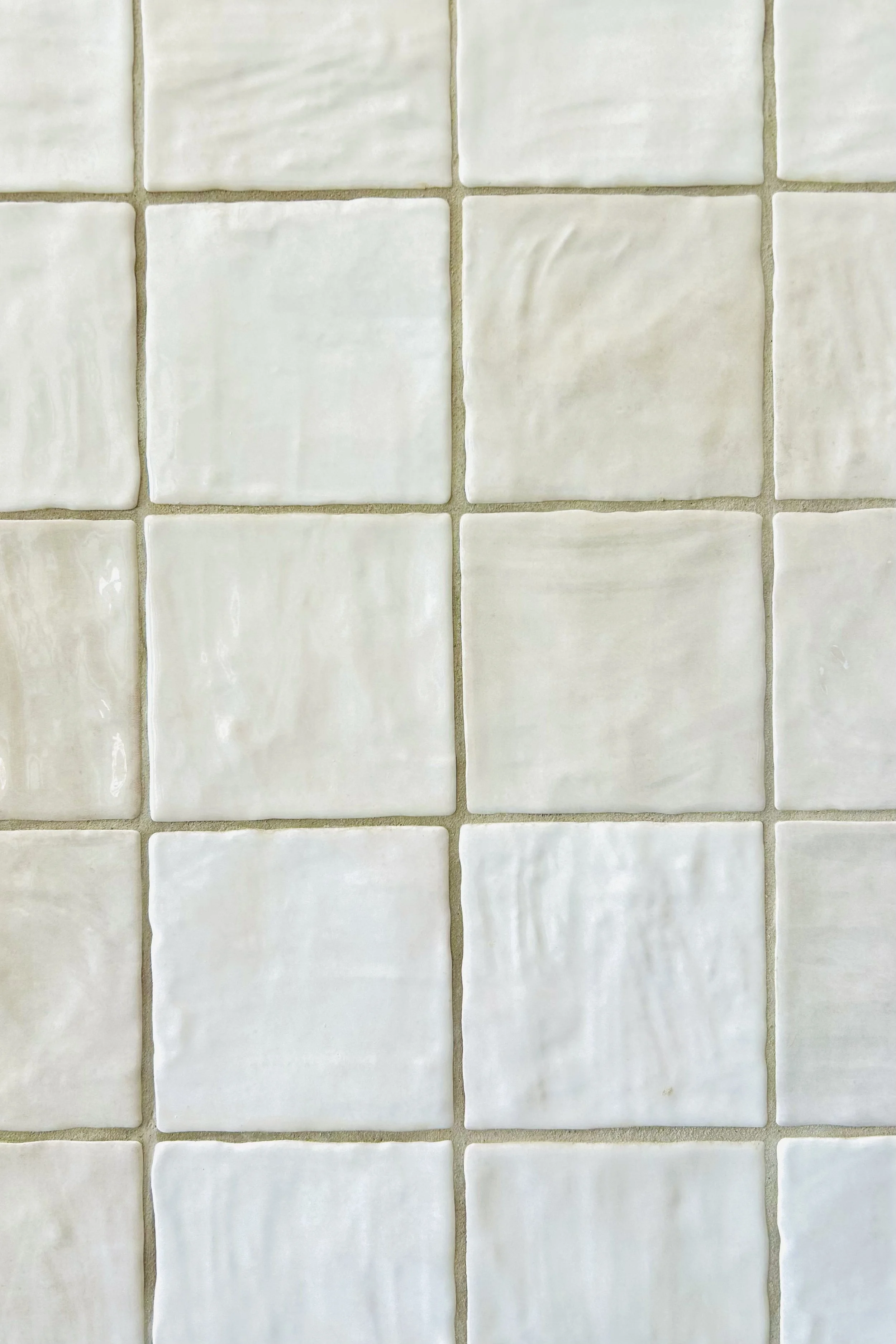Close-up of handmade-look square riad tiles with softly varied glaze creating texture and warmth in the farmhouse kitchen.