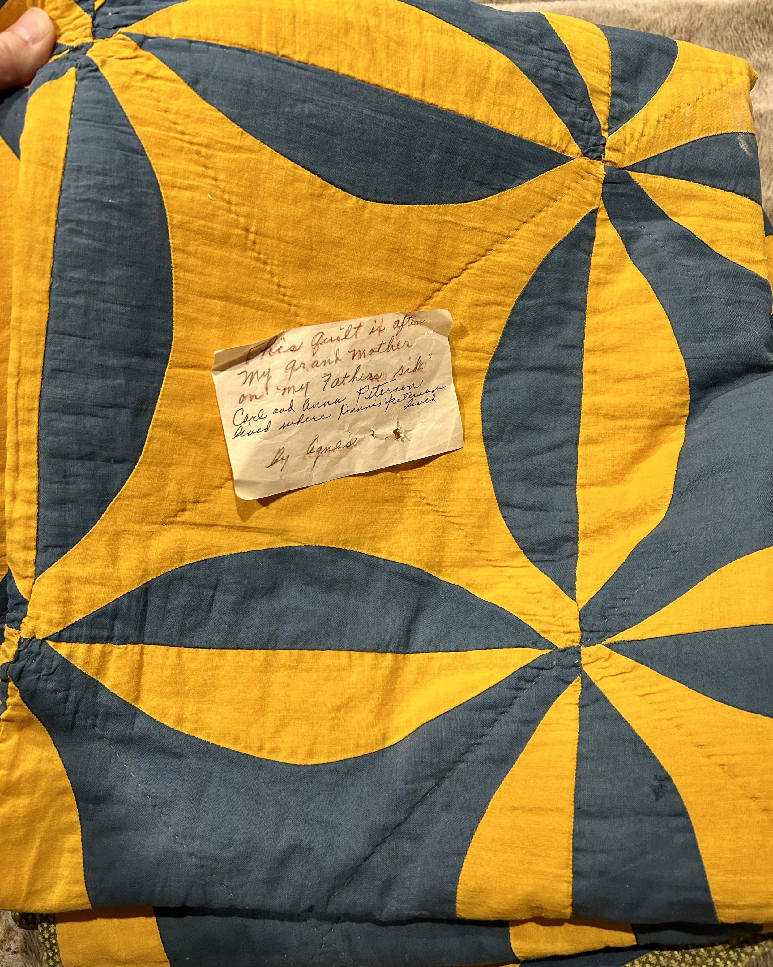Close-up of a family heirloom quilt with a handwritten note documenting its Norwegian family history.