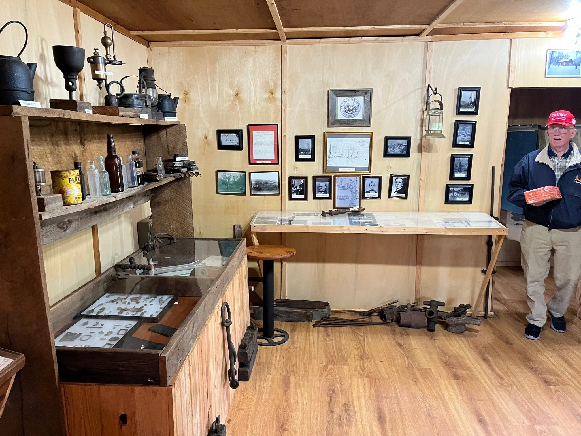 A man stands in a small museum with historical artifacts and photographs on the walls.