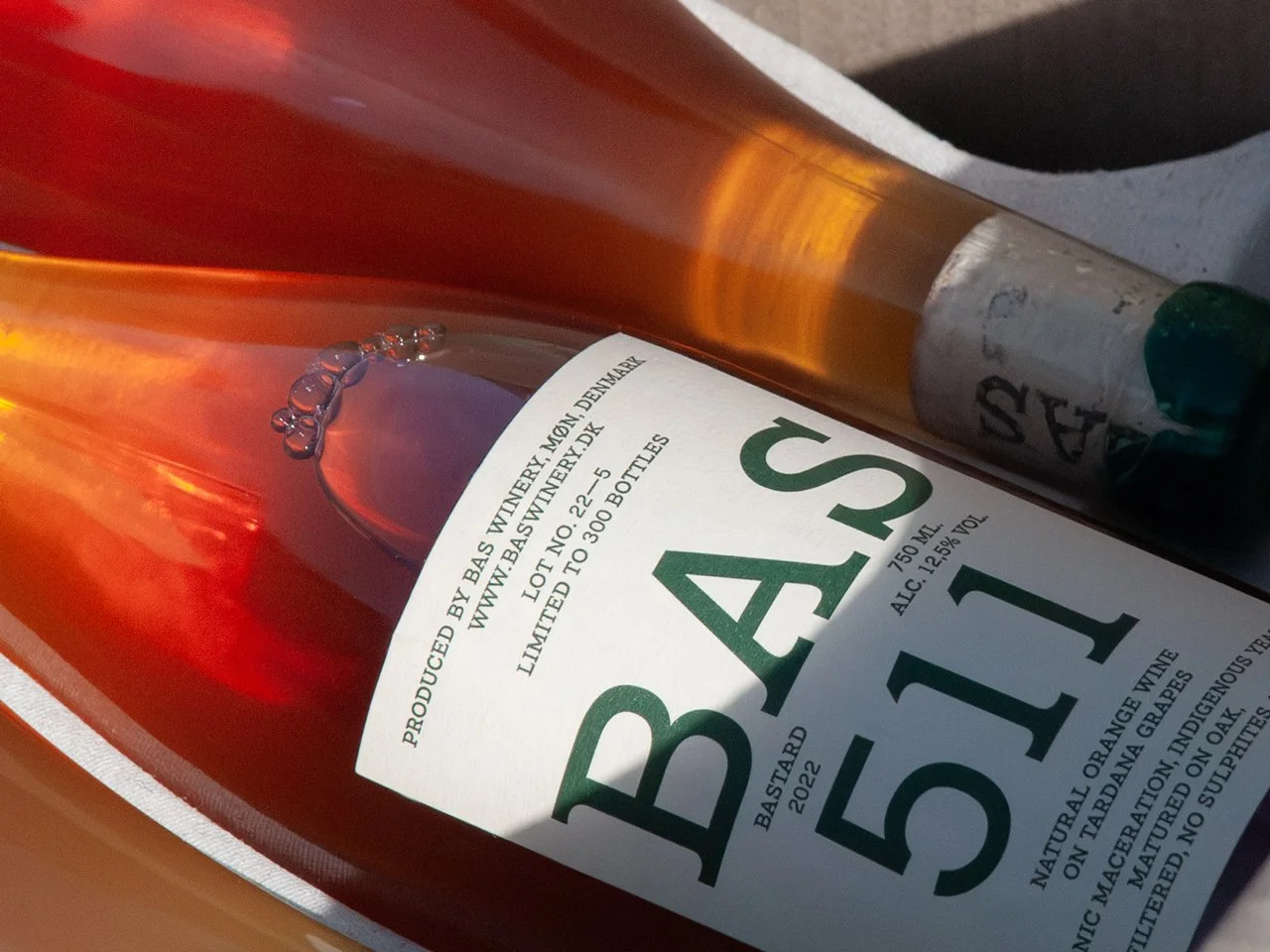 Close-up of a Bas wine bottle lying on its side, showing the label with details about the wine's origin, alcohol content, and volume.