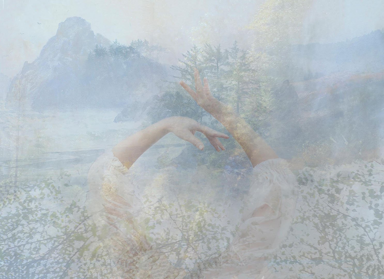A double exposure image featuring a pair of hands in a ballet pose, with a landscape of mountains, trees, and water faintly overlaid.