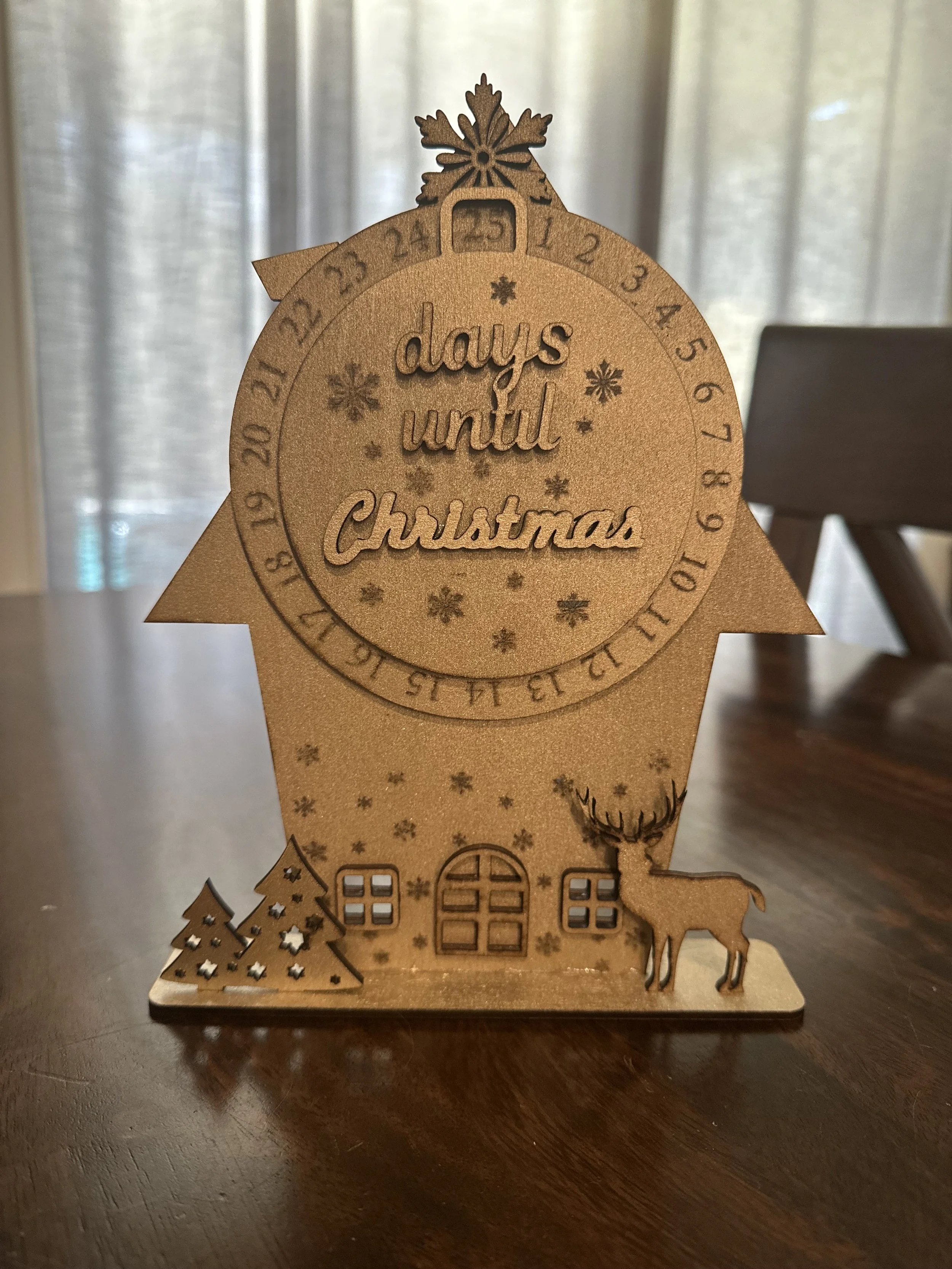 Wooden Christmas countdown ornament with a reindeer, Christmas trees, and the phrase 'days until Christmas' inside a circle with numbers from 1 to 25.