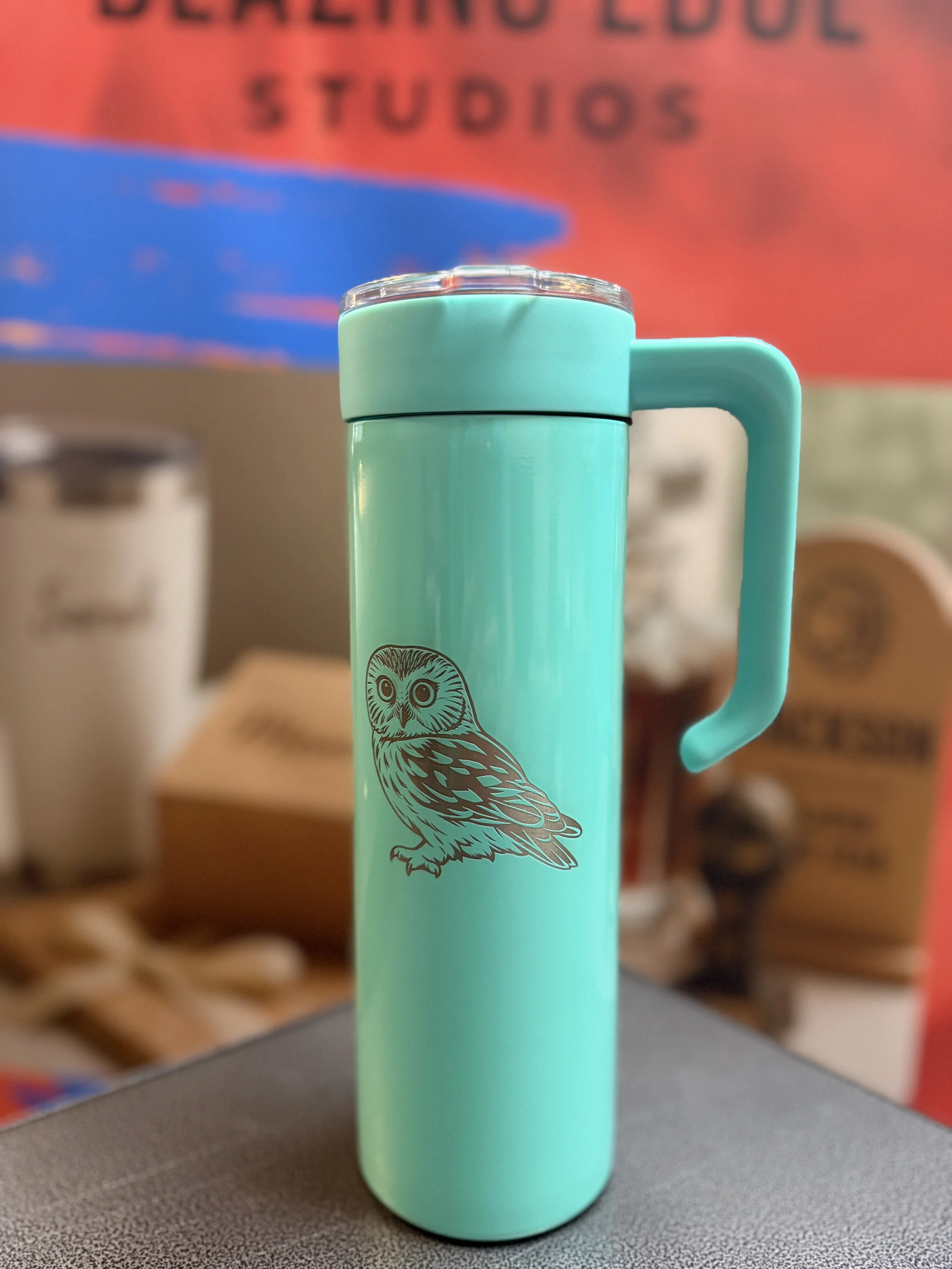 An engraved 20 oz skinny tumbler with handle in aqua color, featuring the smallest owl in North America