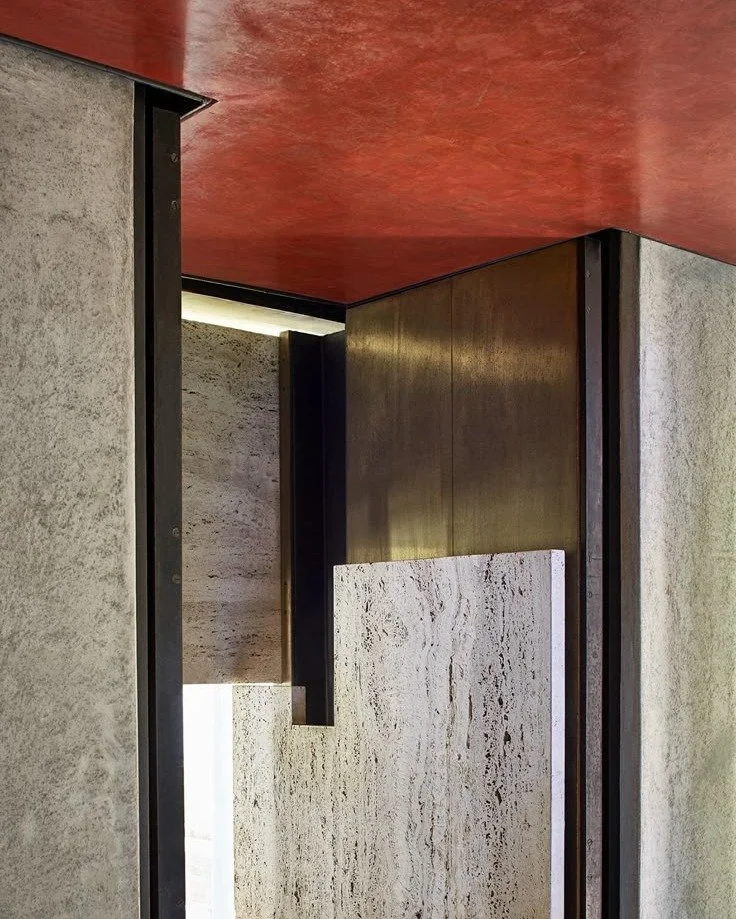 Interior corner with textured concrete walls, a dark metal frame, a dark brown wooden panel, and a red ceiling.