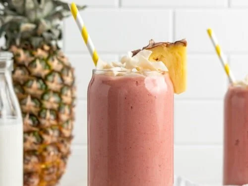 A vibrant strawberry and pineapple smoothie in a glass, topped with fruit pieces, representing an energizing weight loss smoothie blend.