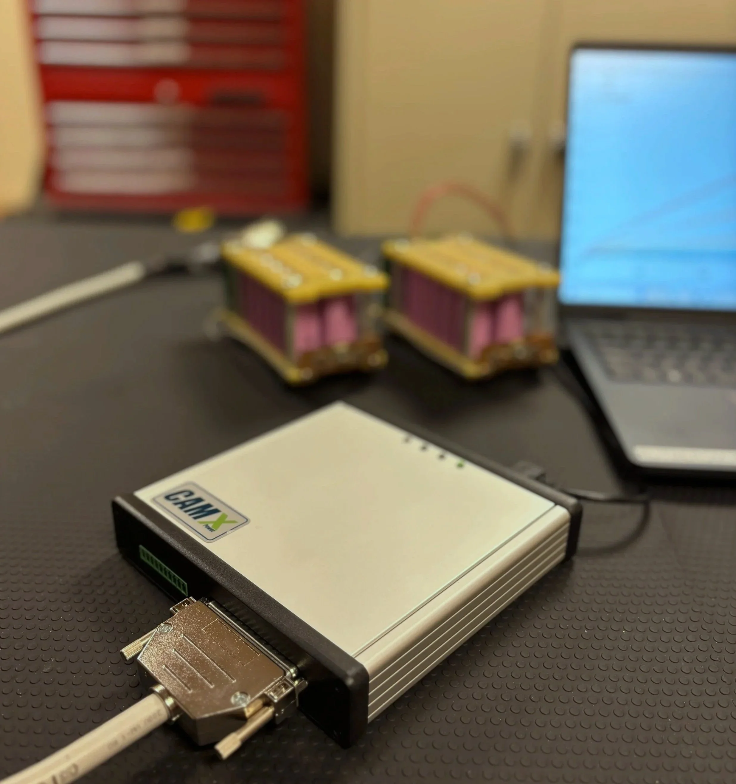 SensLi UDT-S1 pack tester on a workshop bench with interface laptop and packs under test.