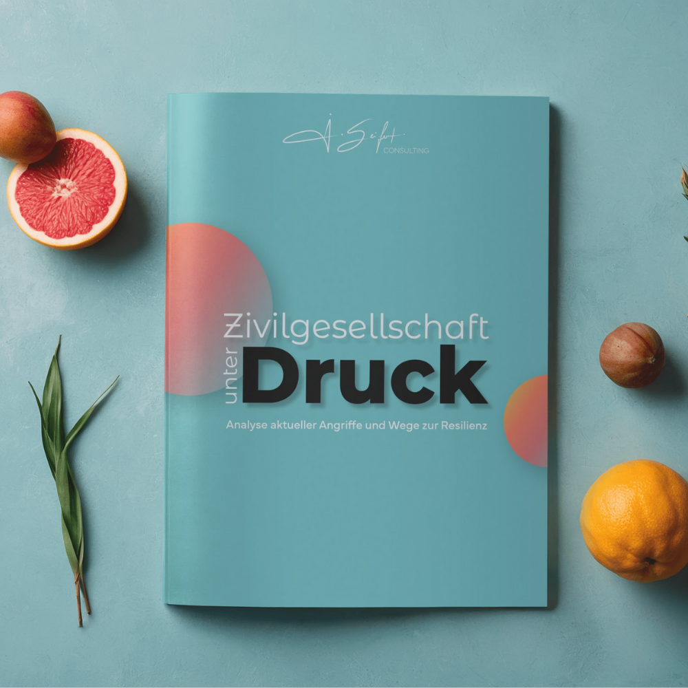 Buch mit dem Titel 'Zivilgesellschaft unter Druck' liegt auf einem blauen Hintergrund, umgeben von einer Grapefruit, einer Zitrone, einer Tomate und einem grünen Blatt.