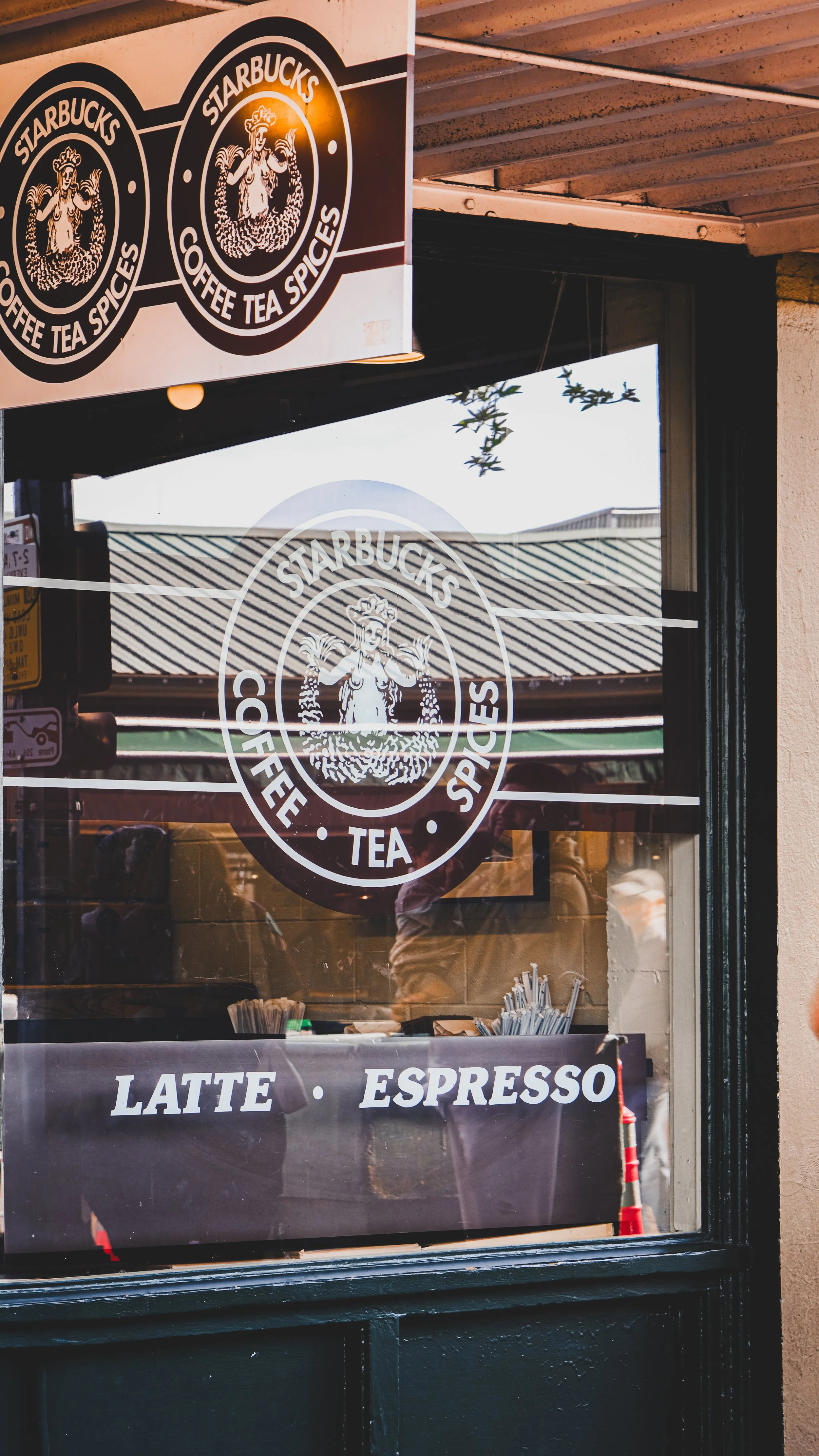 Close-up of a Starbucks coffee shop window with the Starbucks logo, and signs indicating the availability of latte and espresso.