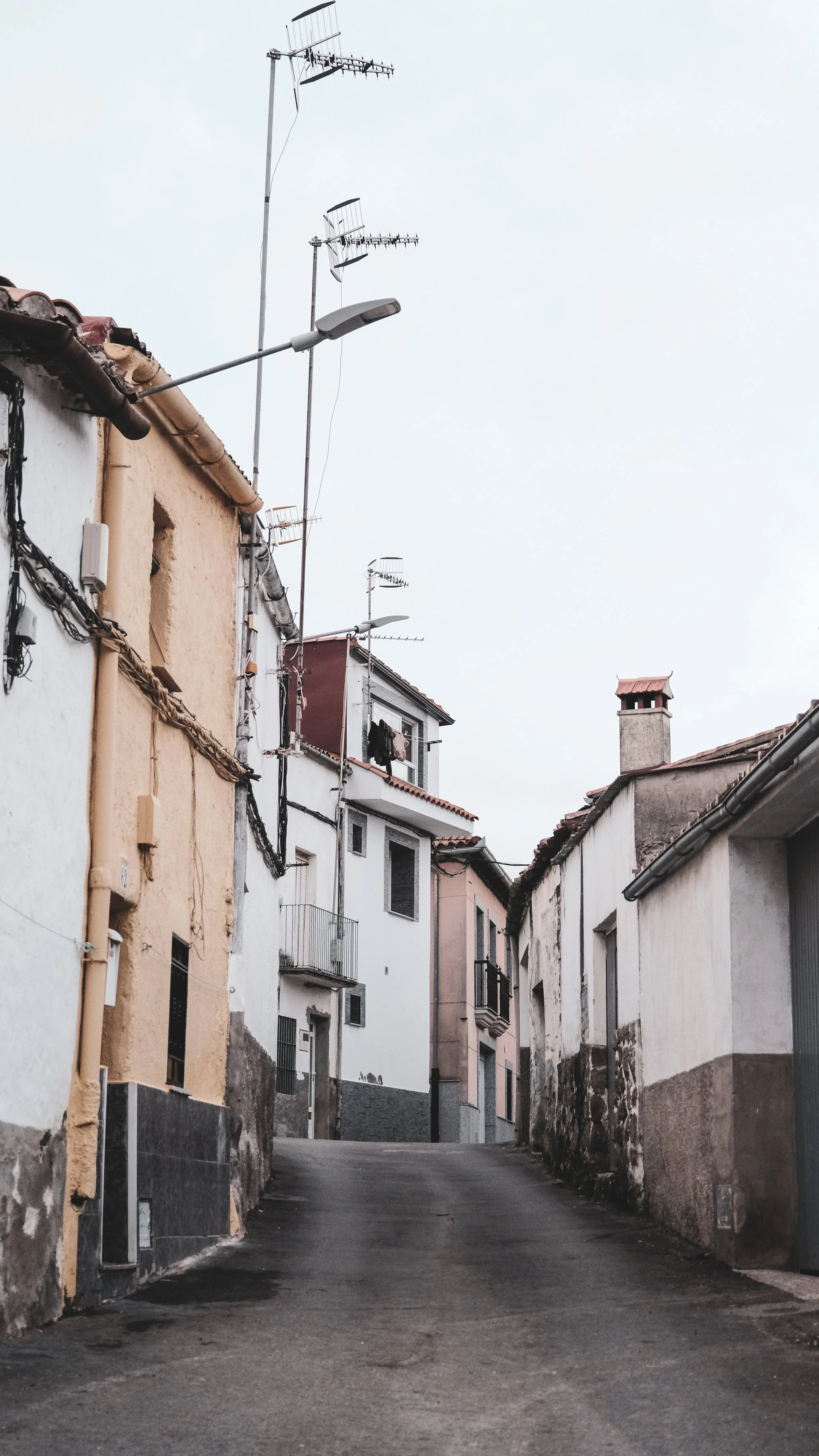 Narrow street in a residential neighborhood with colorful houses and television antennas on rooftops.