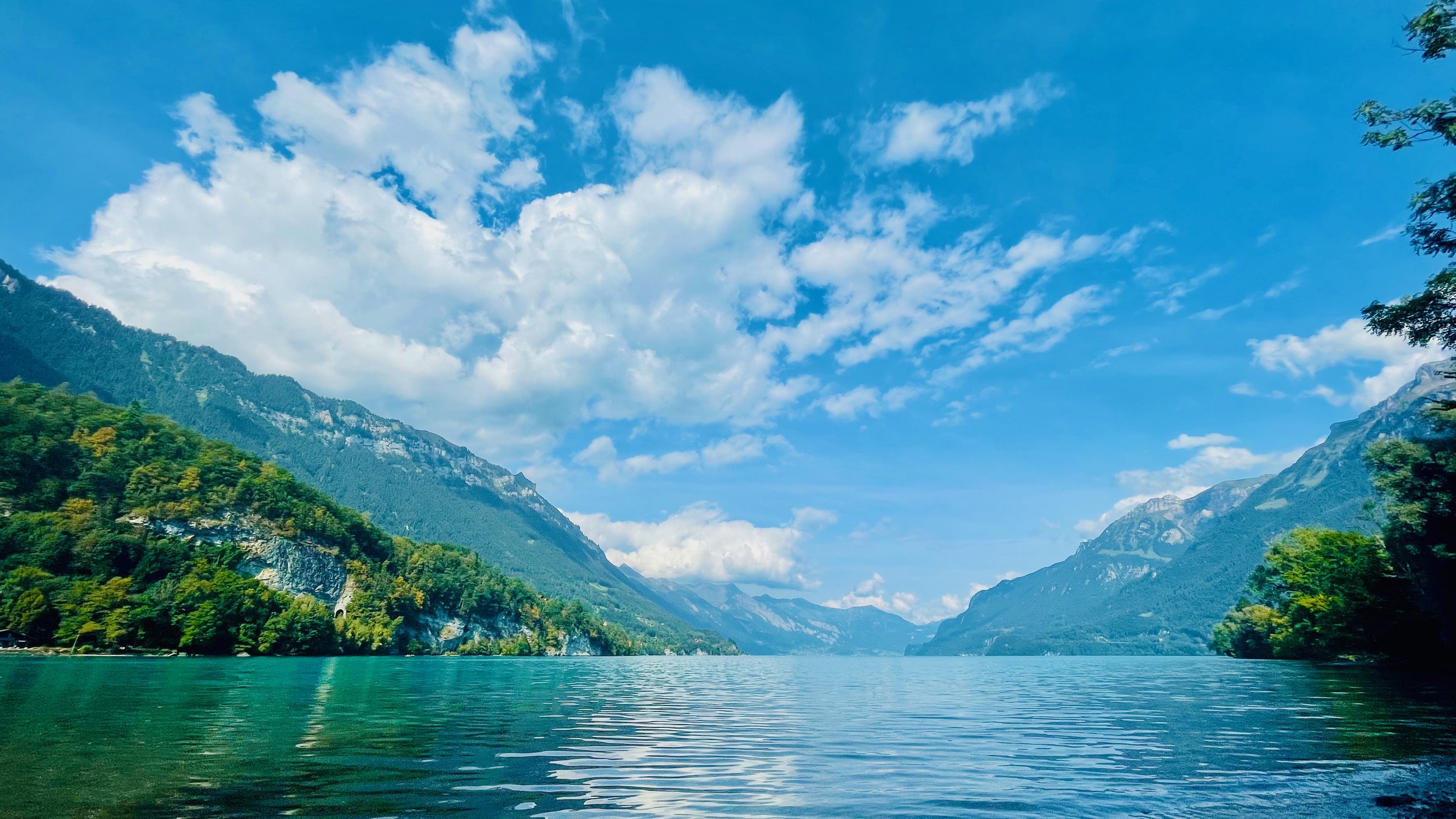 Serene lake with surrounding mountains and clear blue sky.