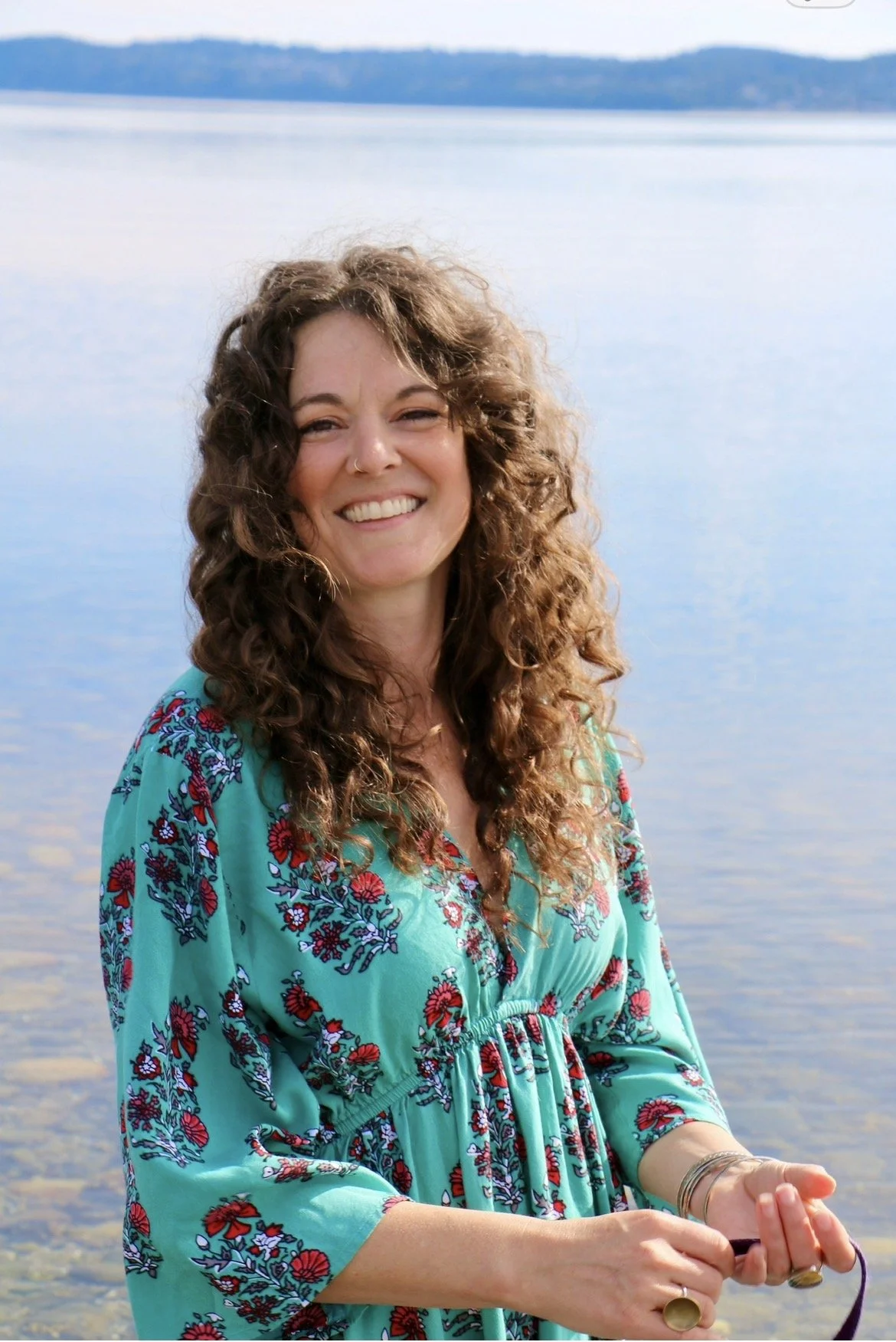 “Katie Weber, Ayurvedic practitioner and yoga teacher, smiling by the water.”