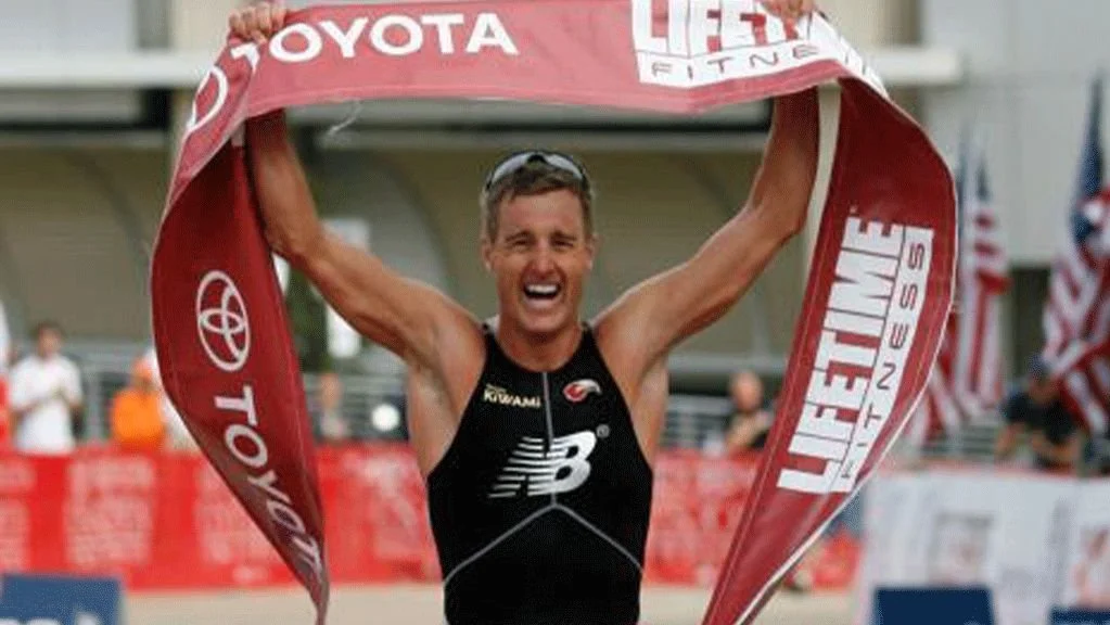 Greg Bennet running across the finish line with banner in hand