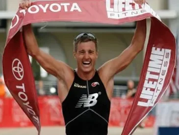 Greg Bennet running across the finish line with banner in hand