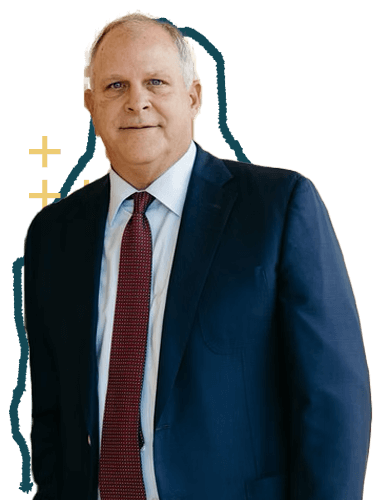 A middle-aged man with short, light-colored hair wearing a dark blue suit, white shirt, and red tie, standing against a plain background.