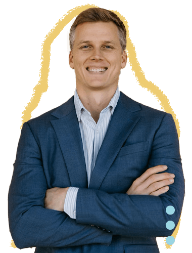 A smiling man in a blue suit with arms crossed, standing against a plain white background.