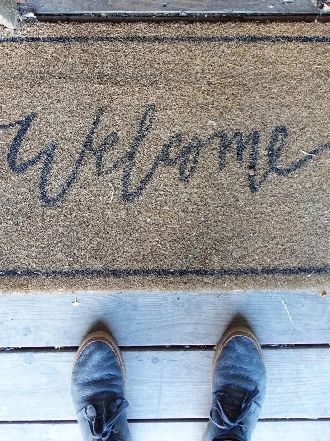 man standing by a mat that says welcome