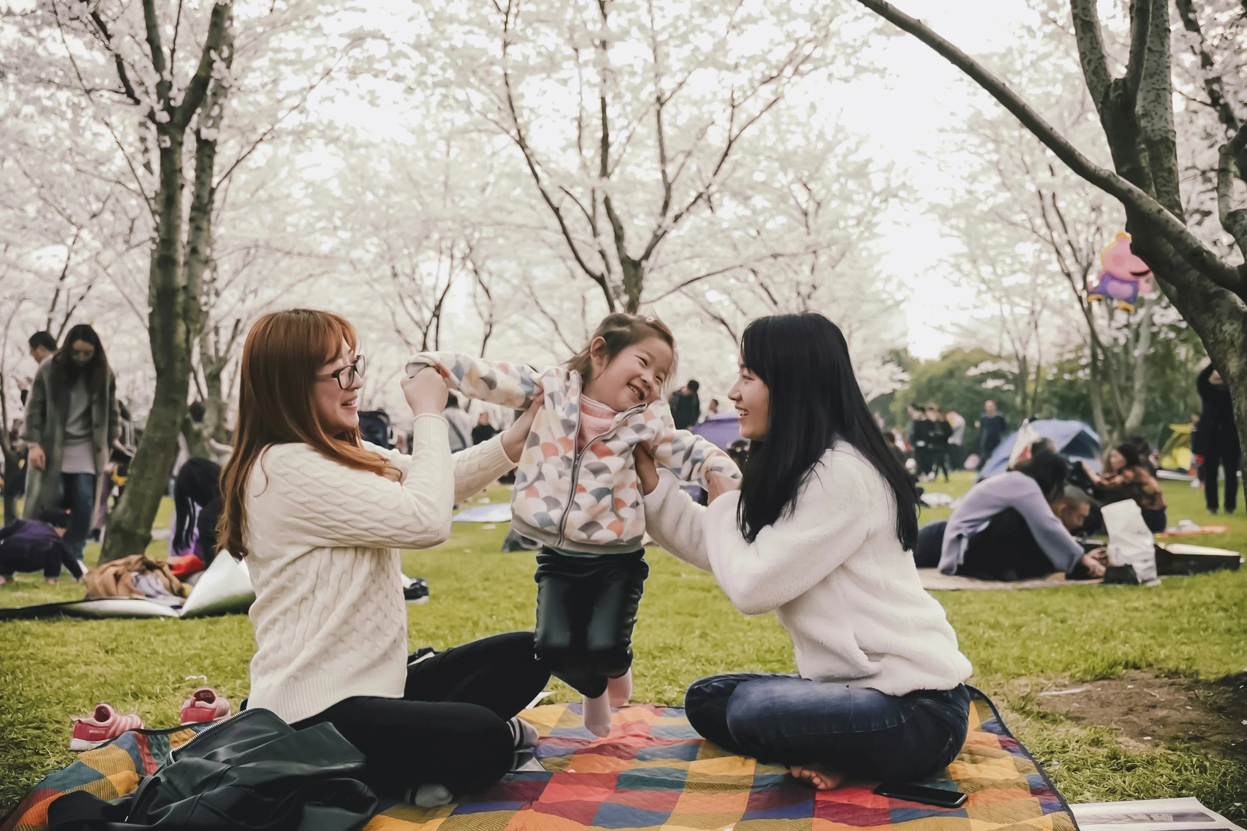 Two mothers and child playing together outdoors, representing family connection